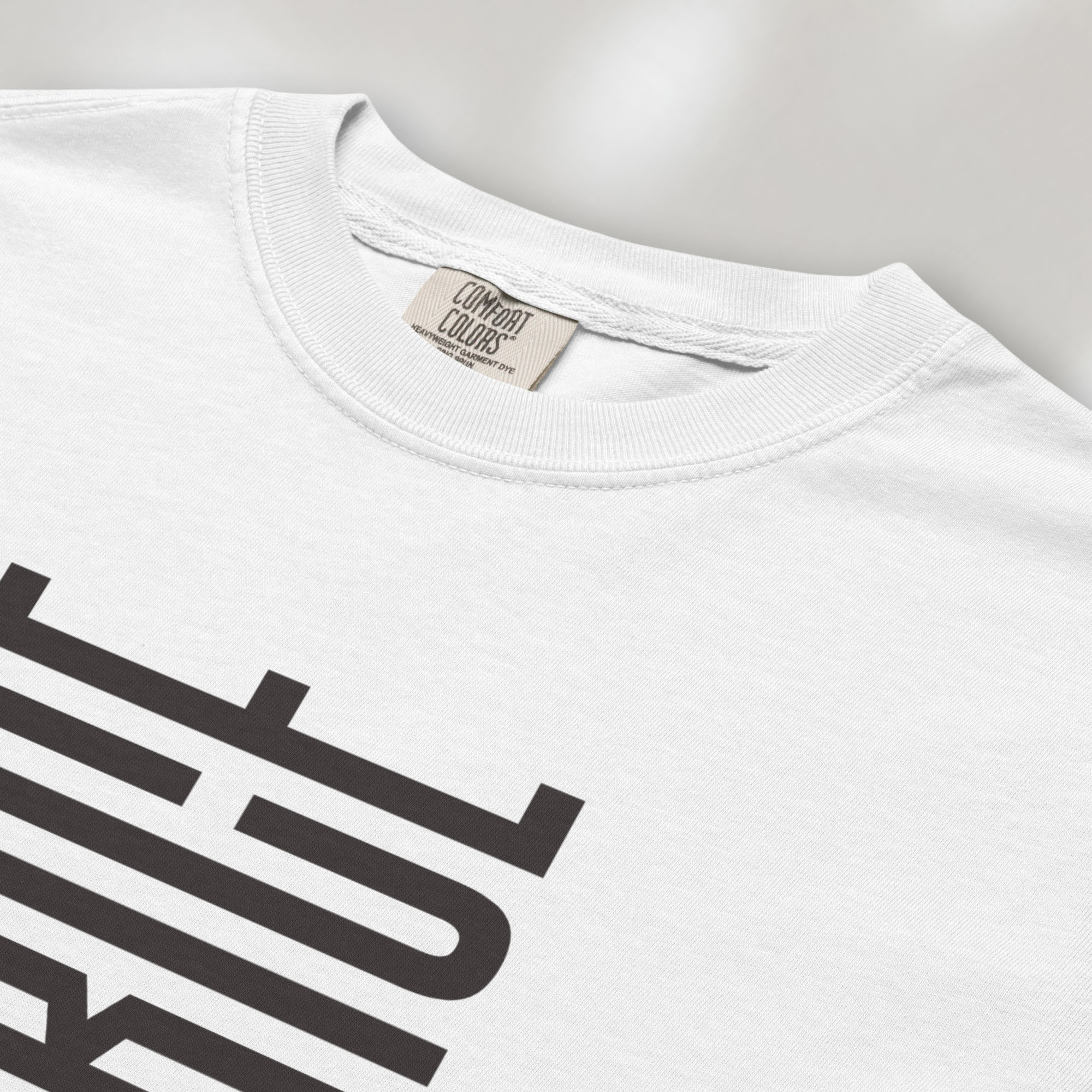 Closeup detail of white t-shirt with minimalist geometric design that subtly spells “Fuck ICE” using stacked bars and negative space, hidden protest message shirt.
