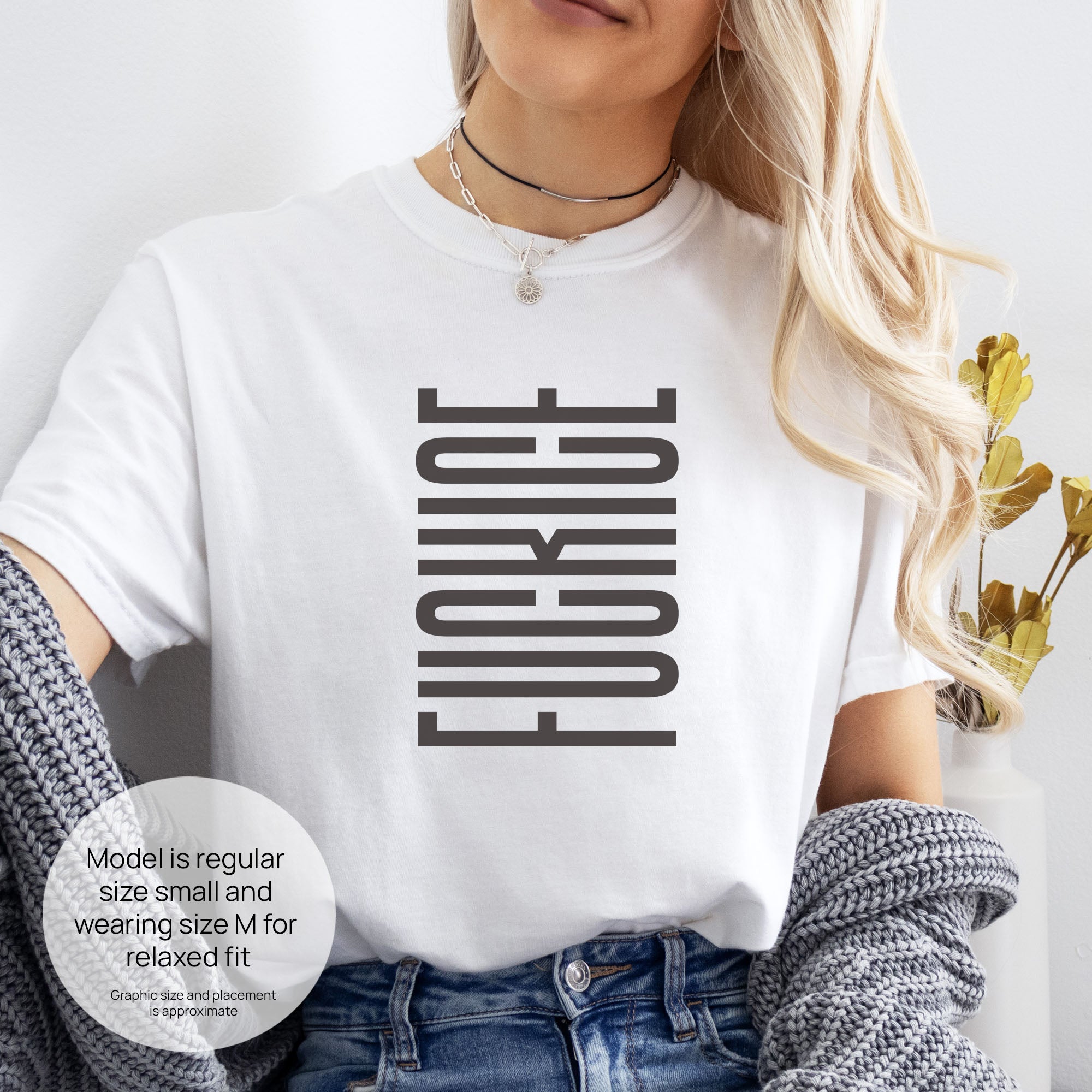 Female model wearing white t-shirt with minimalist geometric design that subtly spells “Fuck ICE” using stacked bars and negative space, hidden protest message shirt. Includes size and fit information for the model who is regular size small, and wearing a size M shirt for a relaxed fit.
