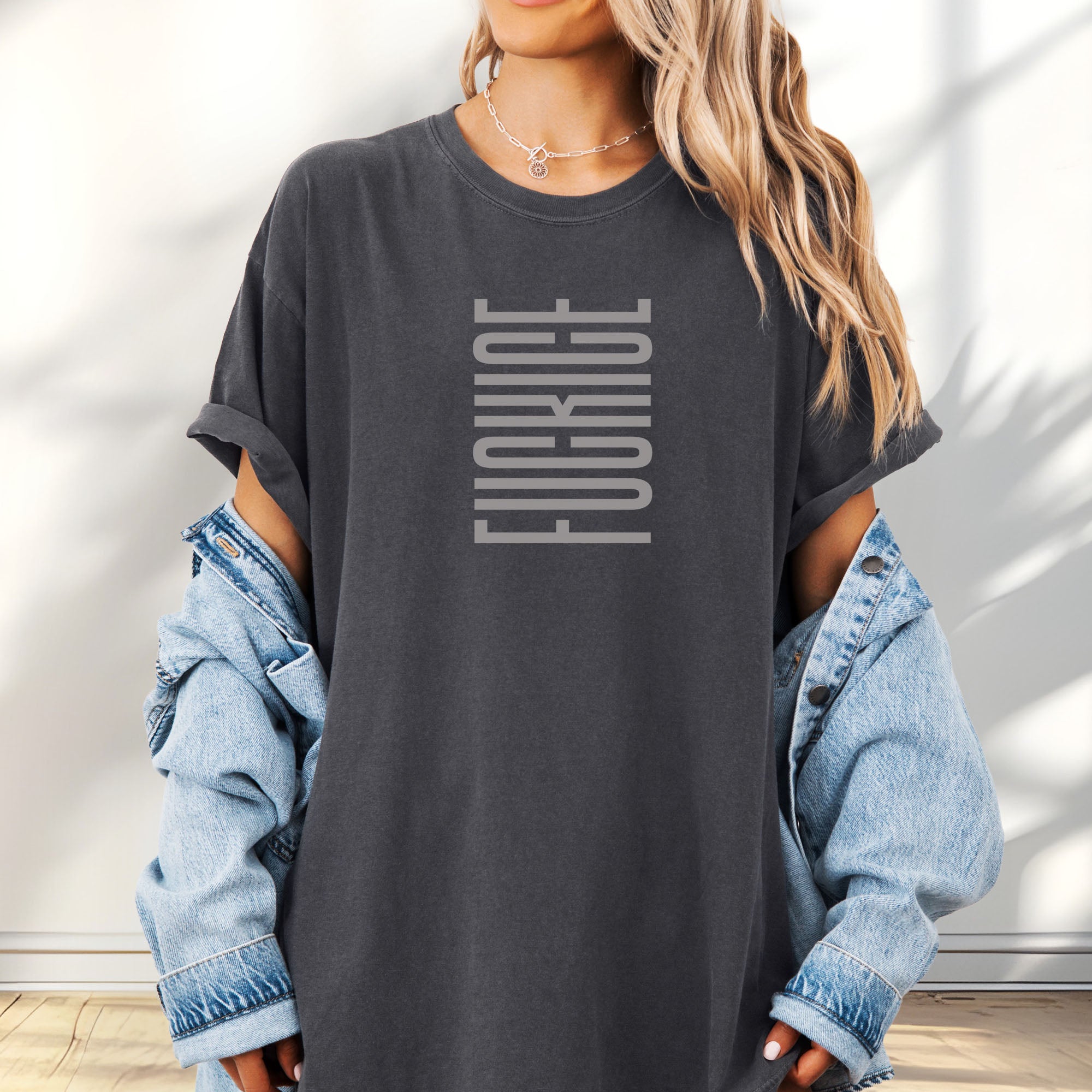 Female model wearing oversized pepper t-shirt with minimalist geometric design that subtly spells “Fuck ICE” using stacked bars and negative space, hidden protest message shirt.