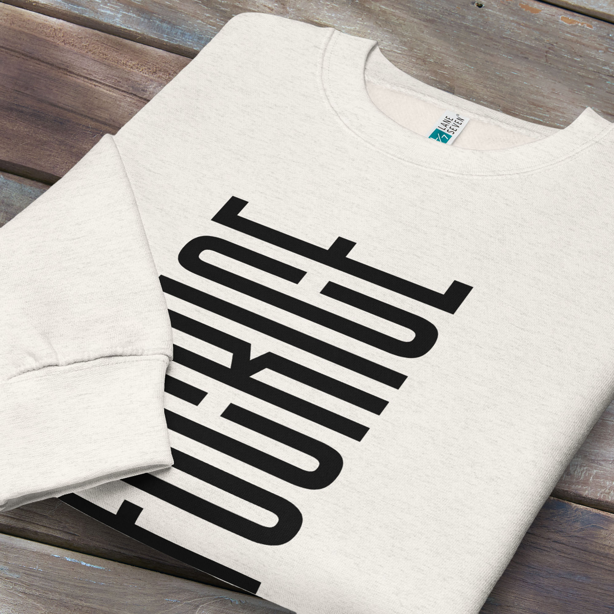 Folded oatmeal sweatshirt with minimalist black geometric design that subtly spells “Fuck ICE” using stacked bars and negative space, hidden protest message shirt.