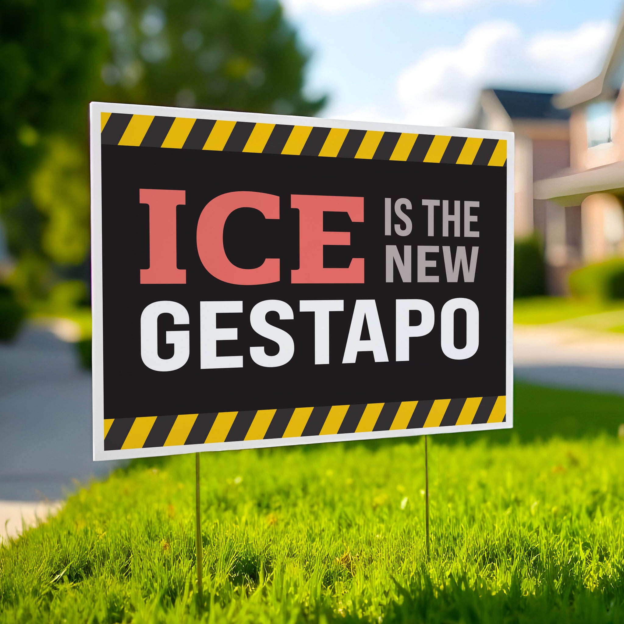 Yard sign in green lawn that reads "ICE is the new gestapo" in strong bold red, grey, and white text on a black background with yellow warning stripes at the top and bottom.