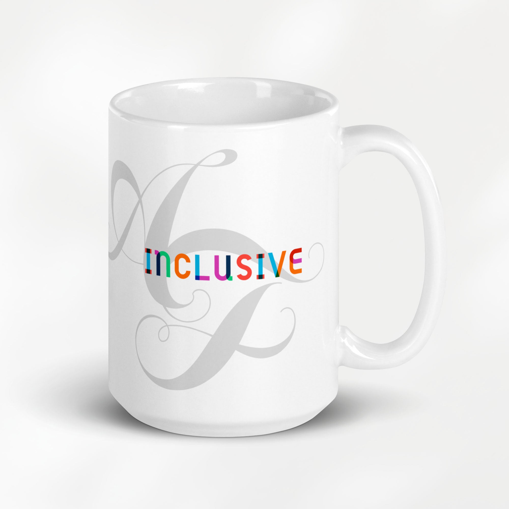 15 ounce white ceramic mug with the word “Inclusive” in colorful Gilbert font and faint script letters A and F behind it.