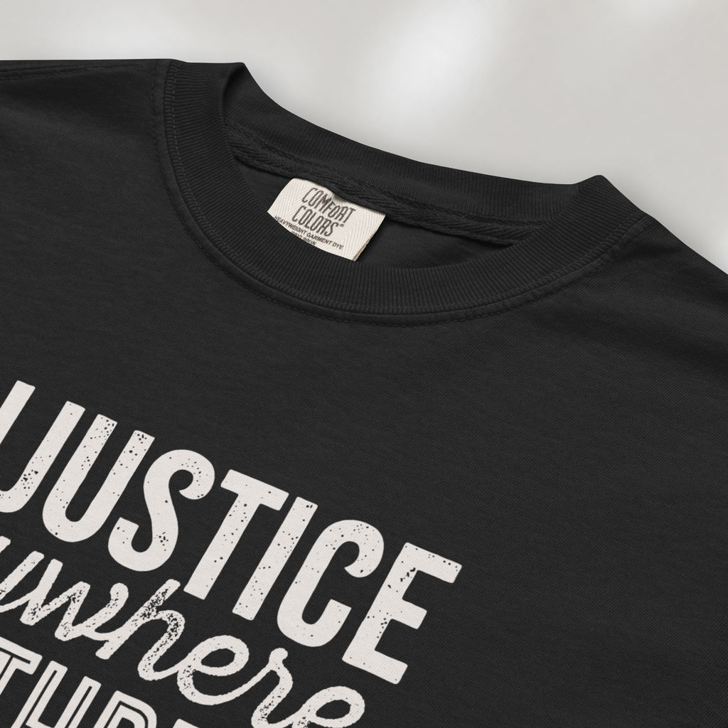 Closeup detail of black t-shirt with bold text reading “Injustice anywhere is a threat to justice everywhere” quote from Martin Luther King Jr, MLK Jr, Letter from Birmingham jail — civil rights protest apparel for activists.
