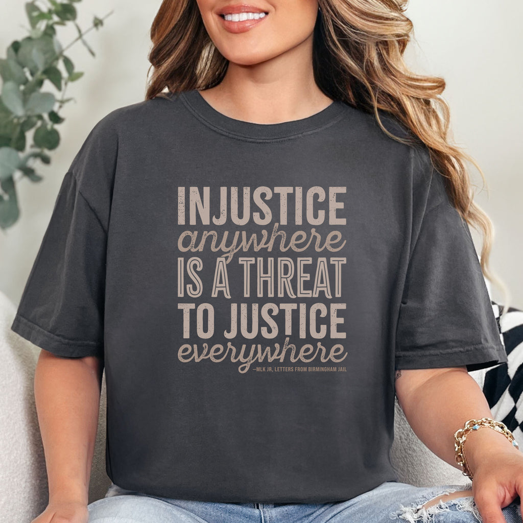 Female model wearing graphite t-shirt with bold text reading “Injustice anywhere is a threat to justice everywhere” quote from Martin Luther King Jr, MLK Jr, Letters from Birmingham jail — civil rights protest apparel for activists.