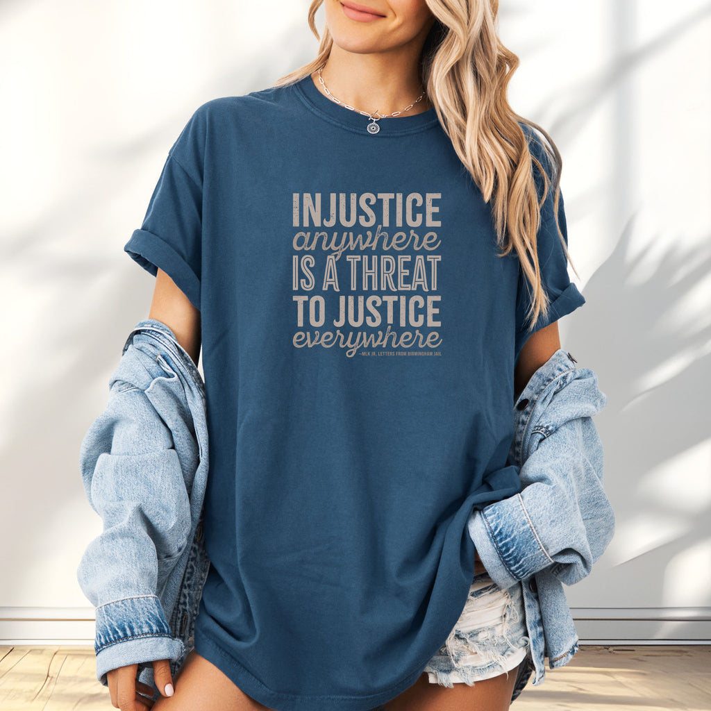 Female model wearing midnight t-shirt with bold text reading “Injustice anywhere is a threat to justice everywhere” quote from Martin Luther King Jr, MLK Jr, Letters from Birmingham jail — civil rights protest apparel for activists.