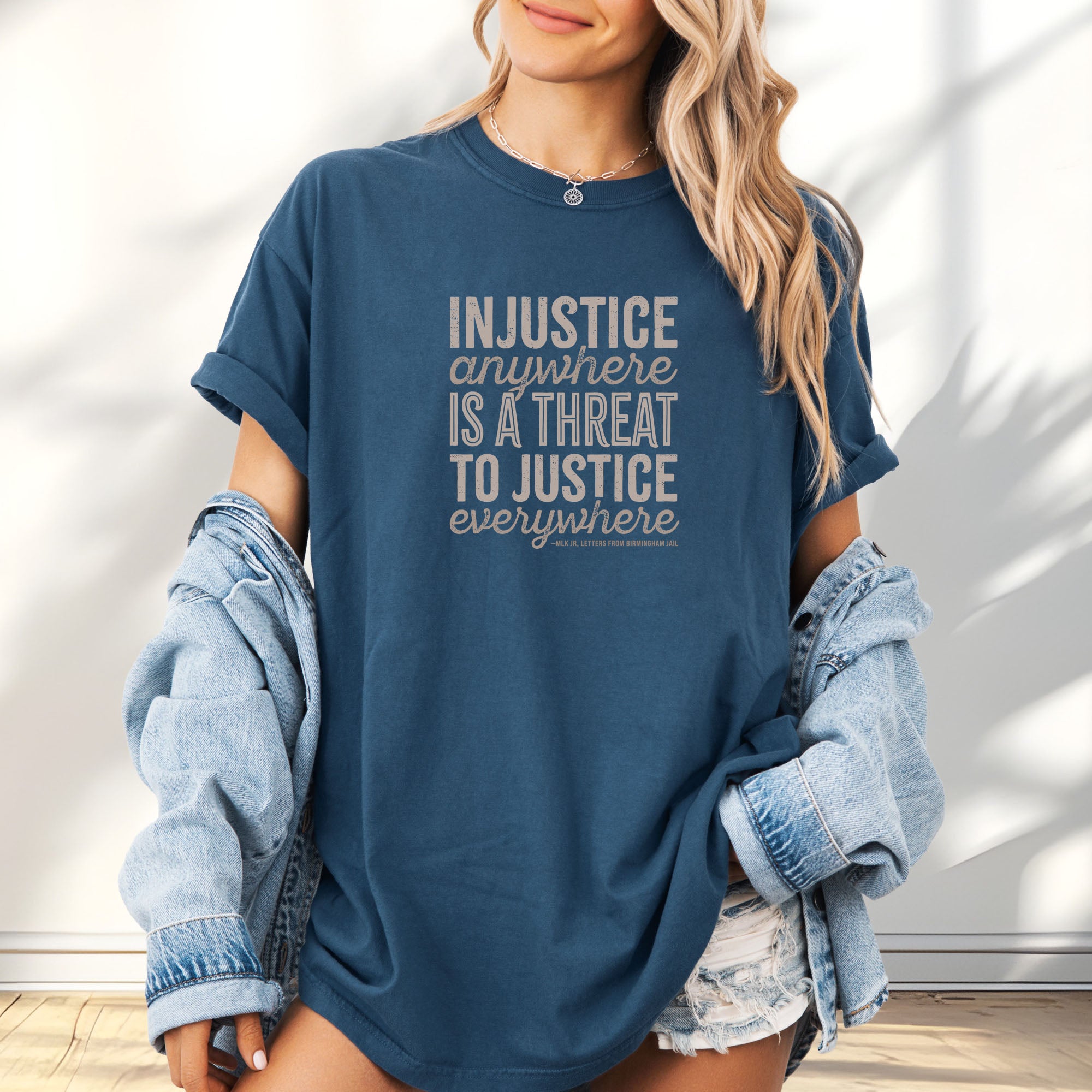 Female model wearing midnight t-shirt with bold text reading “Injustice anywhere is a threat to justice everywhere” quote from Martin Luther King Jr, MLK Jr, Letters from Birmingham jail — civil rights protest apparel for activists.