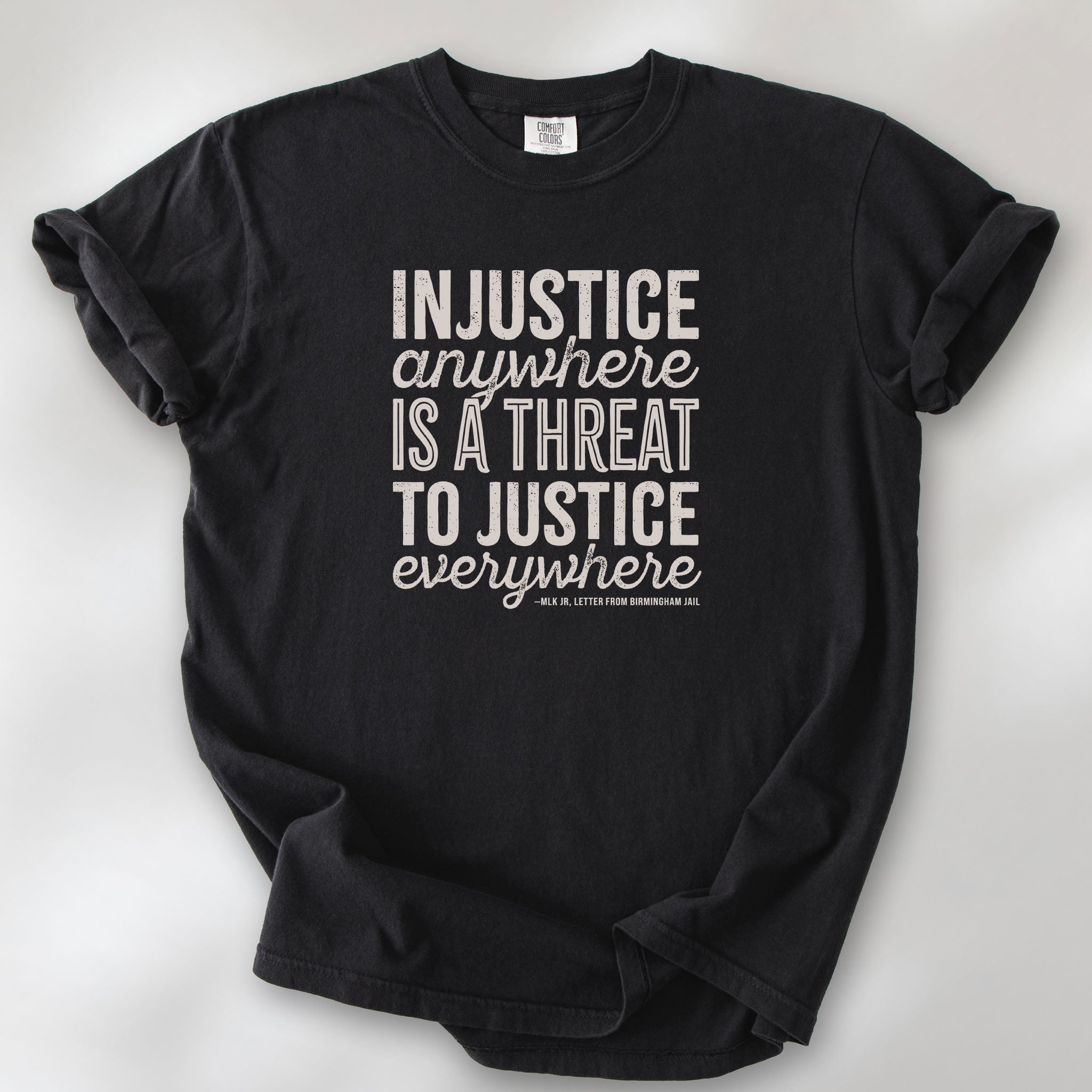 Black t-shirt with bold text reading “Injustice anywhere is a threat to justice everywhere” quote from Martin Luther King Jr, MLK Jr, Letter from Birmingham jail — civil rights protest apparel for activists.