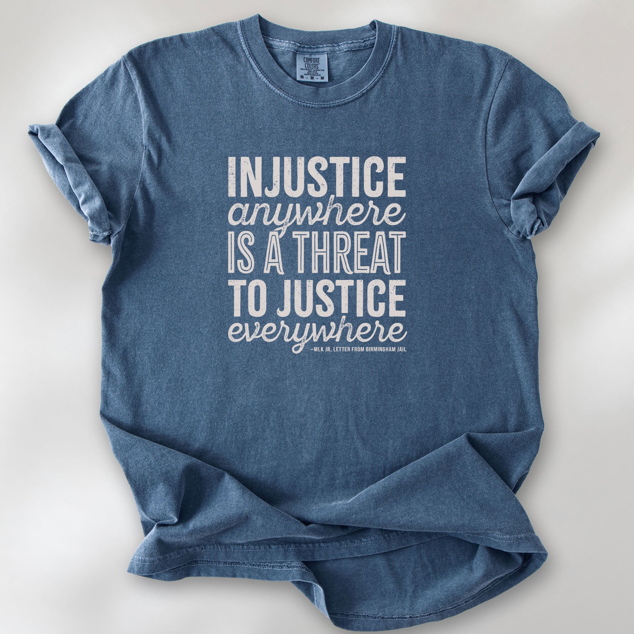Denim t-shirt with bold text reading “Injustice anywhere is a threat to justice everywhere” quote from Martin Luther King Jr, MLK Jr, Letter from Birmingham jail — civil rights protest apparel for activists.
