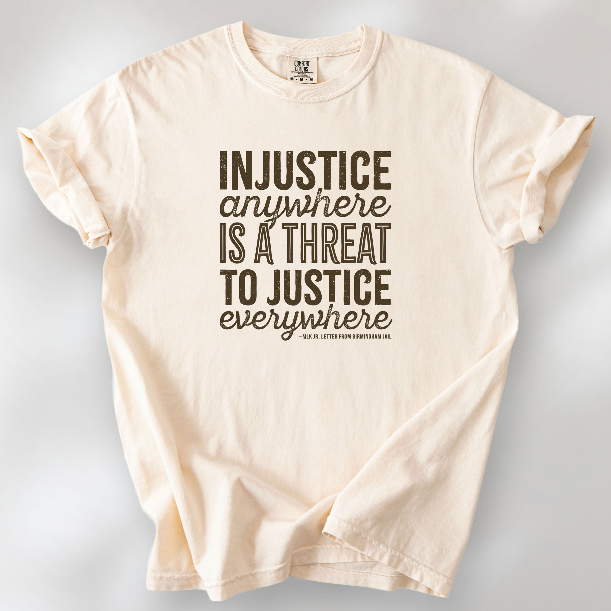 Ivory t-shirt with bold text reading “Injustice anywhere is a threat to justice everywhere” quote from Martin Luther King Jr, MLK Jr, Letter from Birmingham jail — civil rights protest apparel for activists.