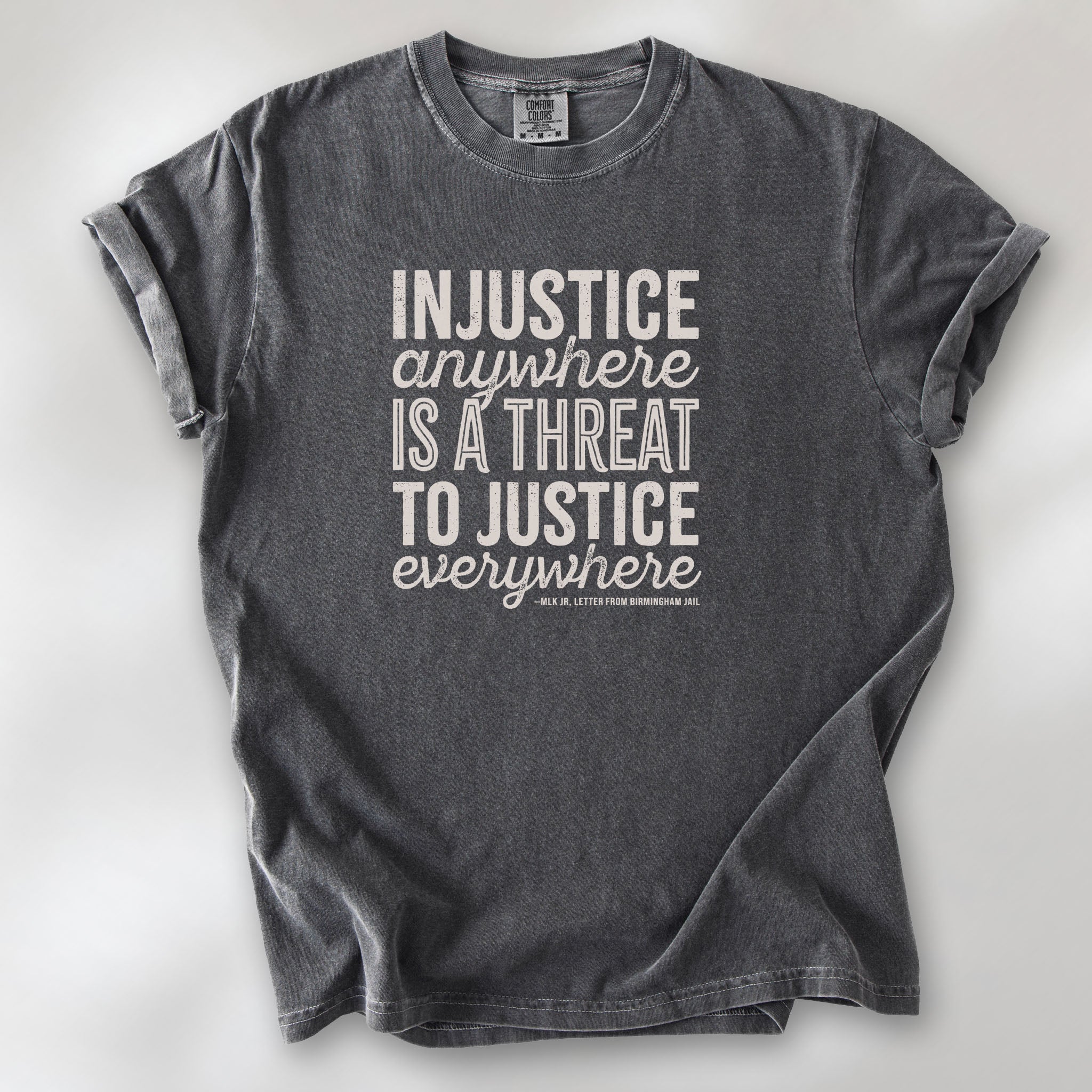 Pepper t-shirt with bold text reading “Injustice anywhere is a threat to justice everywhere” quote from Martin Luther King Jr, MLK Jr, Letter from Birmingham jail — civil rights protest apparel for activists.