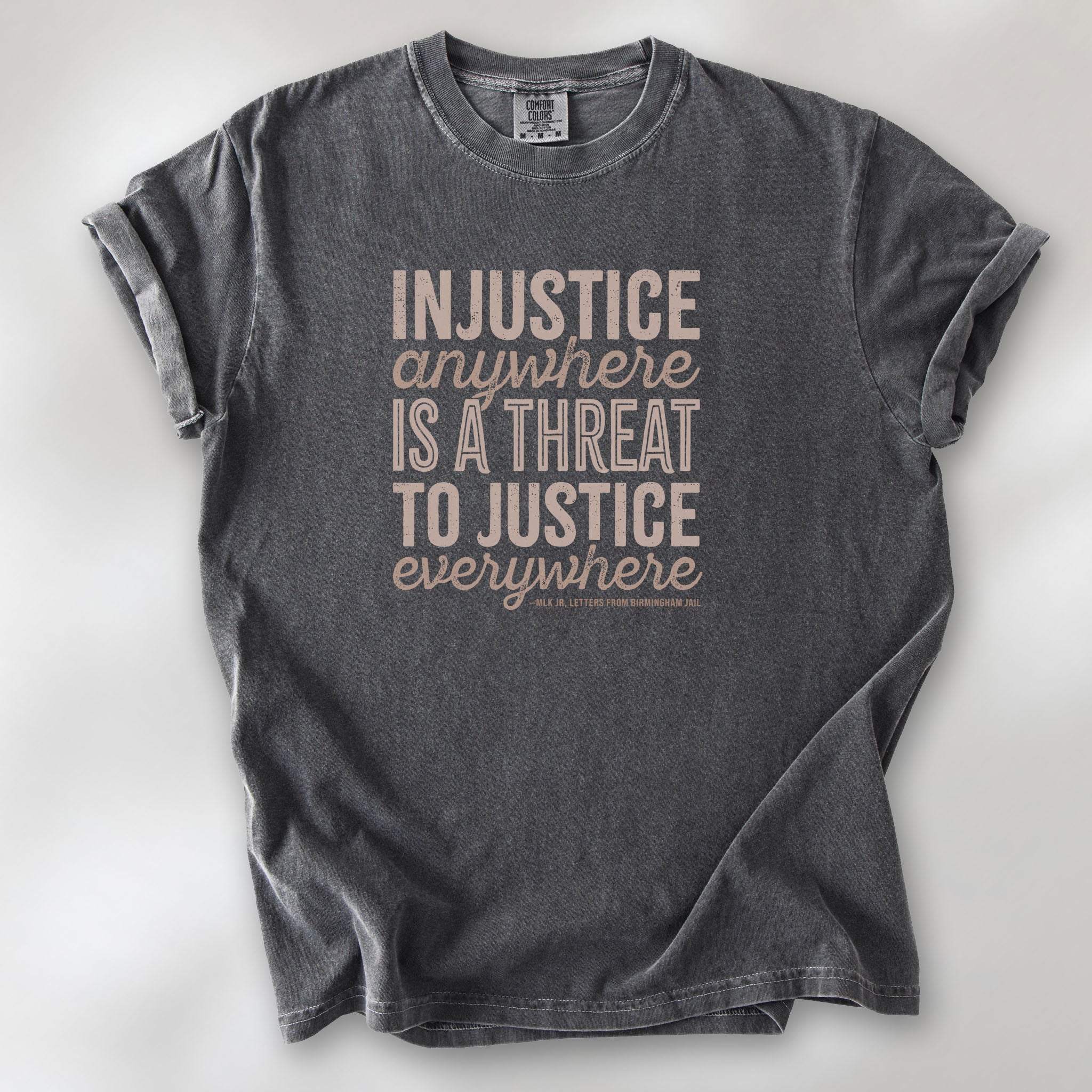 Pepper t-shirt with bold text reading “Injustice anywhere is a threat to justice everywhere” quote from Martin Luther King Jr, MLK Jr, Letters from Birmingham jail — civil rights protest apparel for activists.