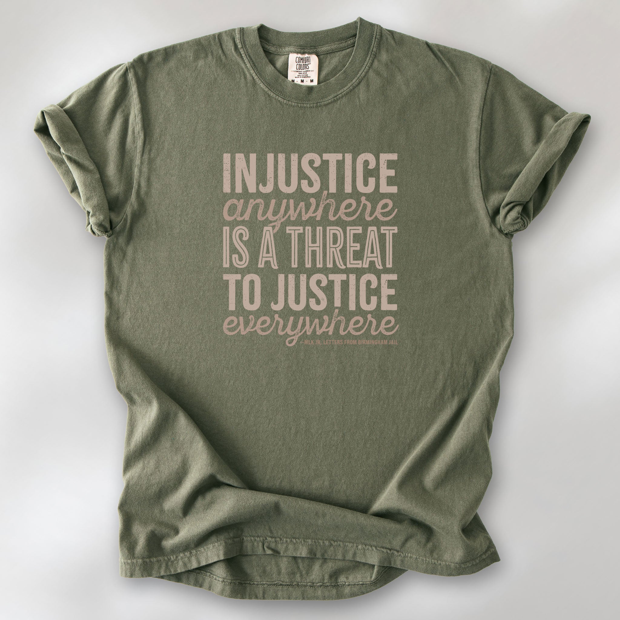 Sage t-shirt with bold text reading “Injustice anywhere is a threat to justice everywhere” quote from Martin Luther King Jr, MLK Jr, Letters from Birmingham jail — civil rights protest apparel for activists.
