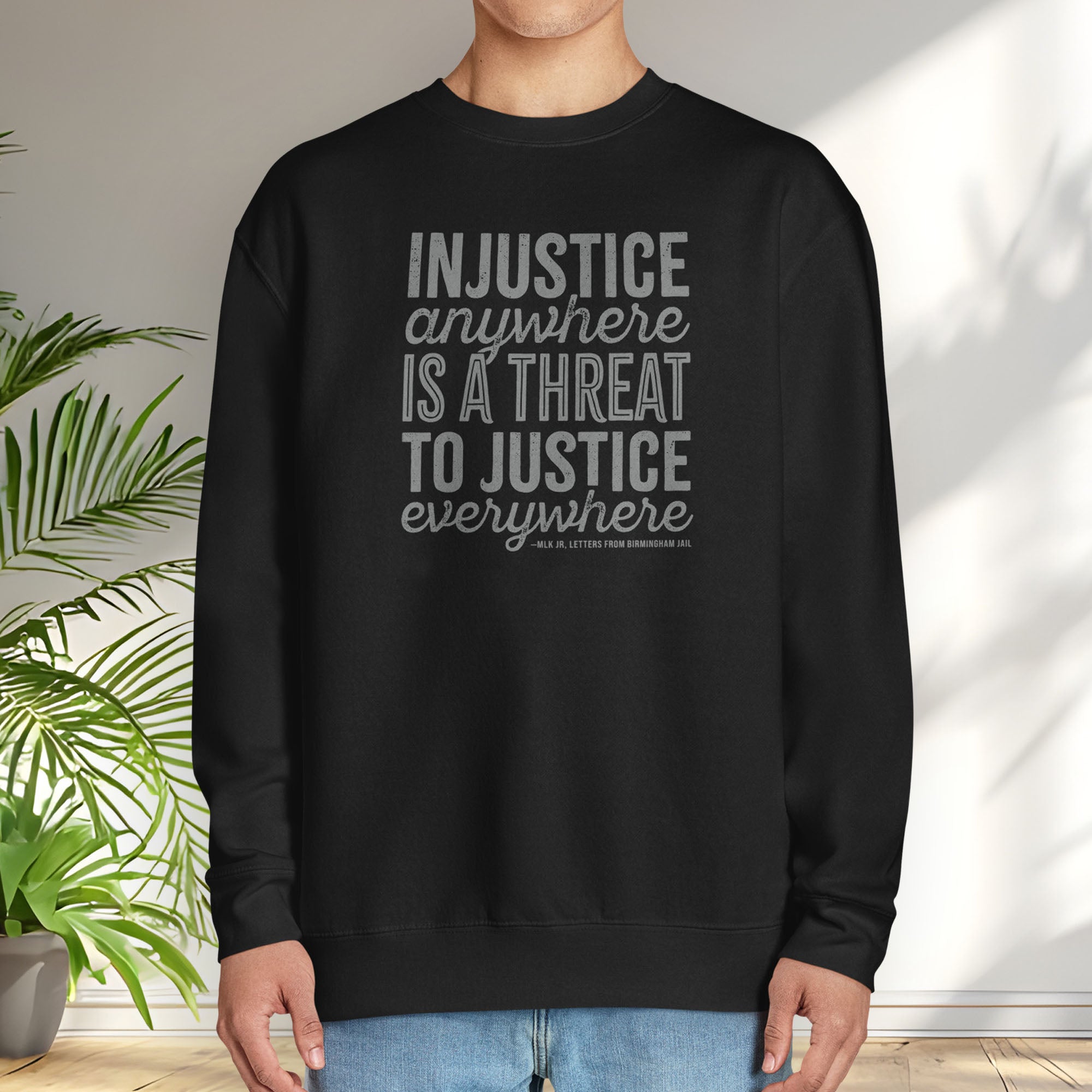 Male model wearing black sweatshirt with bold text reading “Injustice anywhere is a threat to justice everywhere” quote from Martin Luther King Jr, MLK Jr, Letters from Birmingham jail — civil rights protest apparel for activists.