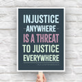 Protest sign with quote from Martin Luther King Jr that reads "injustice anywhere is a threat to justice everywhere" in colorful bold distressed text.