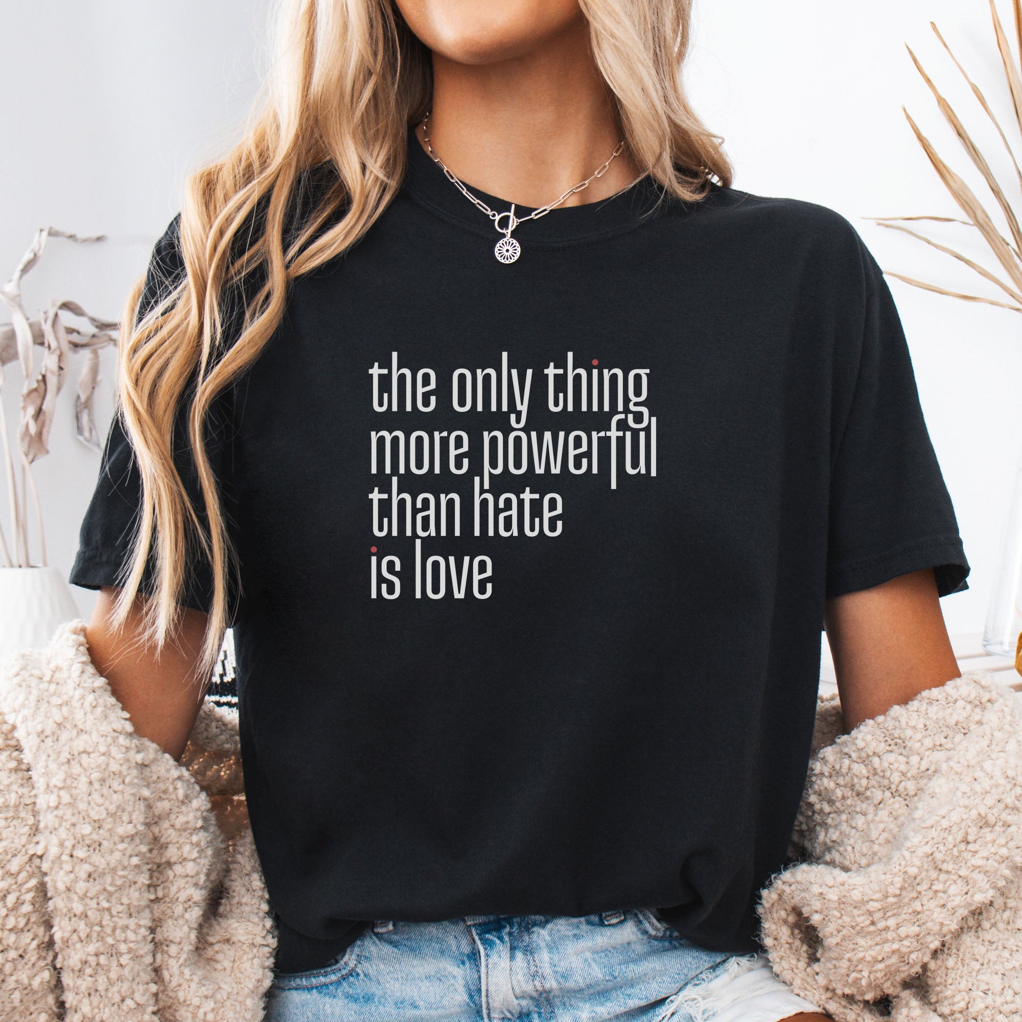 Female model wearing black t-shirt with a stylized text block reading “the only thing more powerful than hate is love."