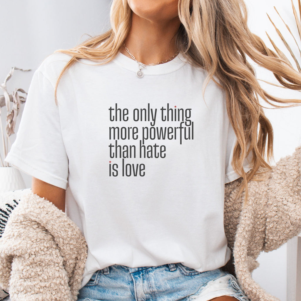 Female model wearing white t-shirt with a stylized text block reading “the only thing more powerful than hate is love."
