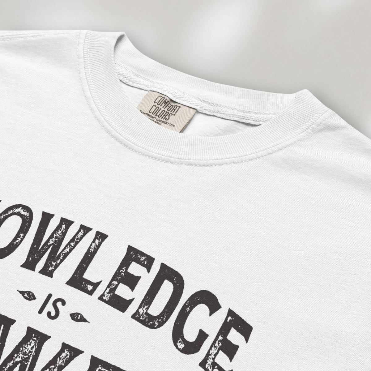 Closeup detail of white t-shirt with vintage style typography reading “Knowledge Is Power – Keep Learning."