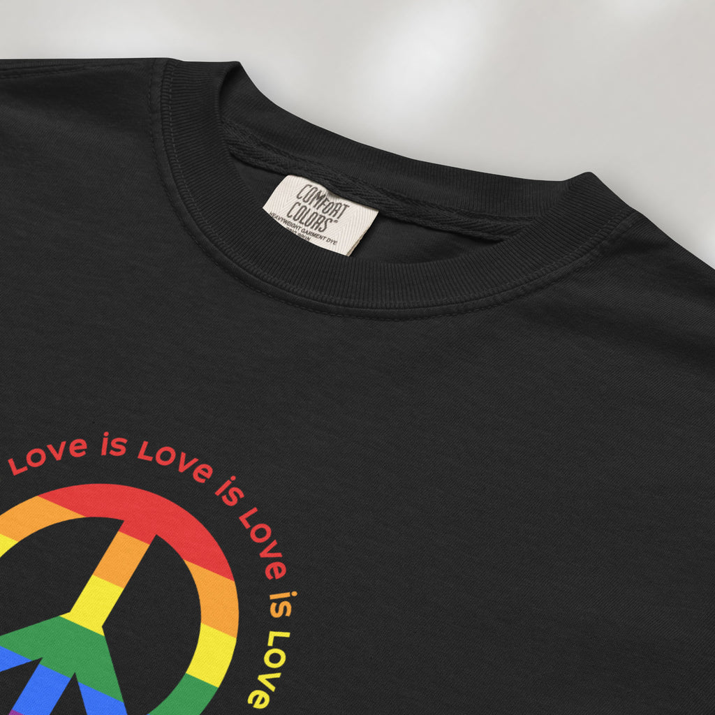 Closeup detail of black t-shirt with LGBTQ pride graphic — a peace sign in the LGBTQ flag colors, with the text "love is love" repeated in a circle around the peace sign.