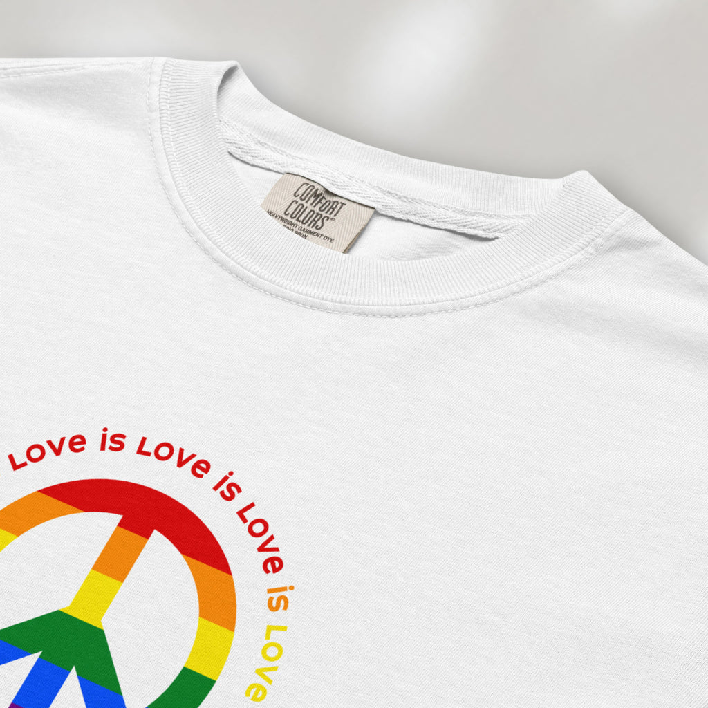 Closeup detail of white t-shirt with LGBTQ pride graphic — a peace sign in the LGBTQ flag colors, with the text "love is love" repeated in a circle around the peace sign.
