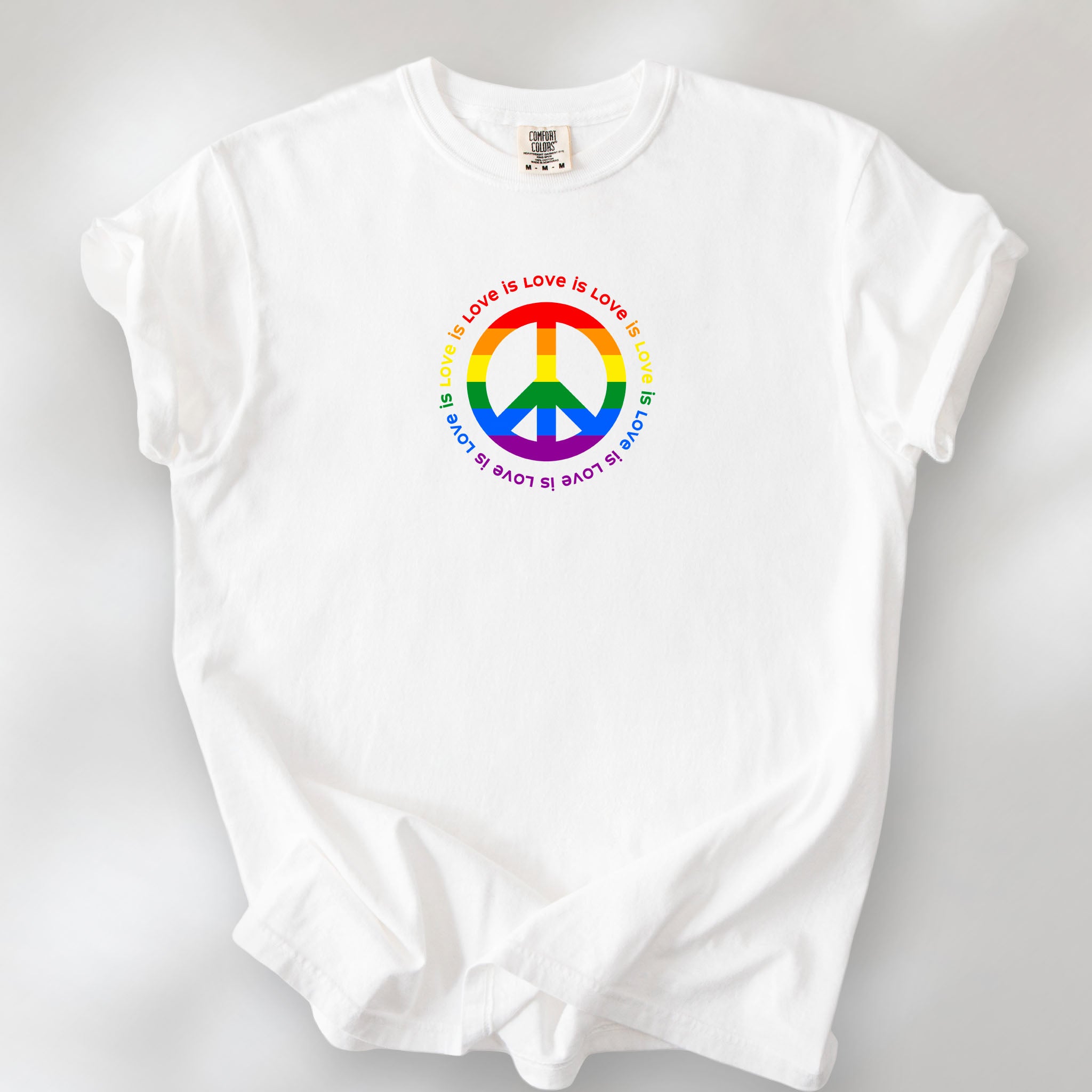 White t-shirt with LGBTQ pride graphic — a peace sign in the LGBTQ flag colors, with the text "love is love" repeated in a circle around the peace sign.