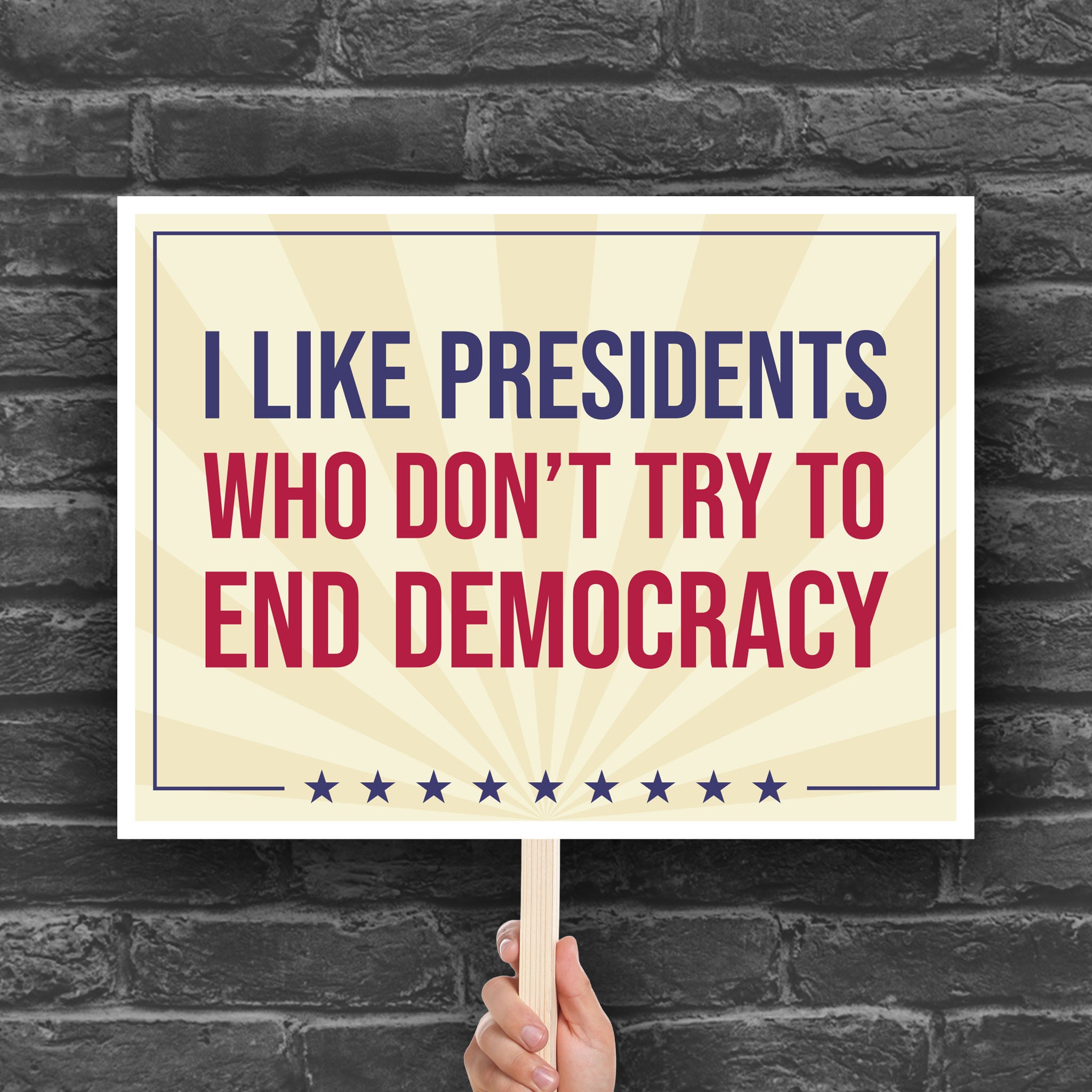 Downloadable, printable protest sign with light gold background and red and blue bold text that reads "I like presidents who don't try to end democracy."