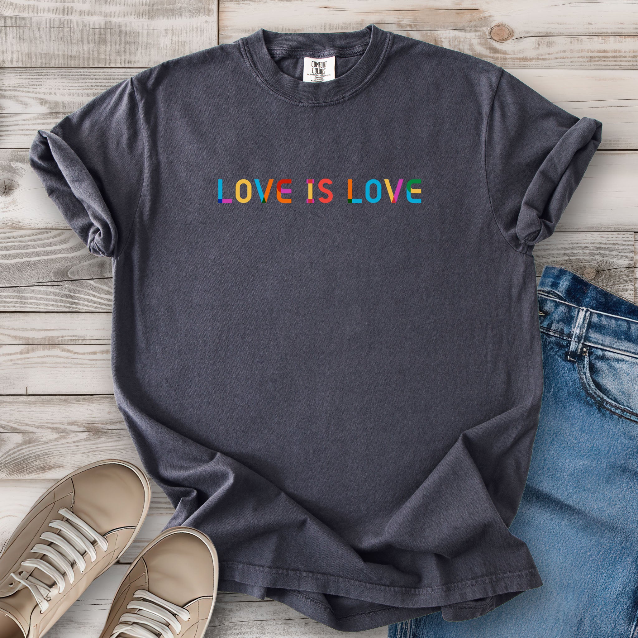Graphite grey t-shirt with rainbow “love is love” text designed in the Gilbert font.