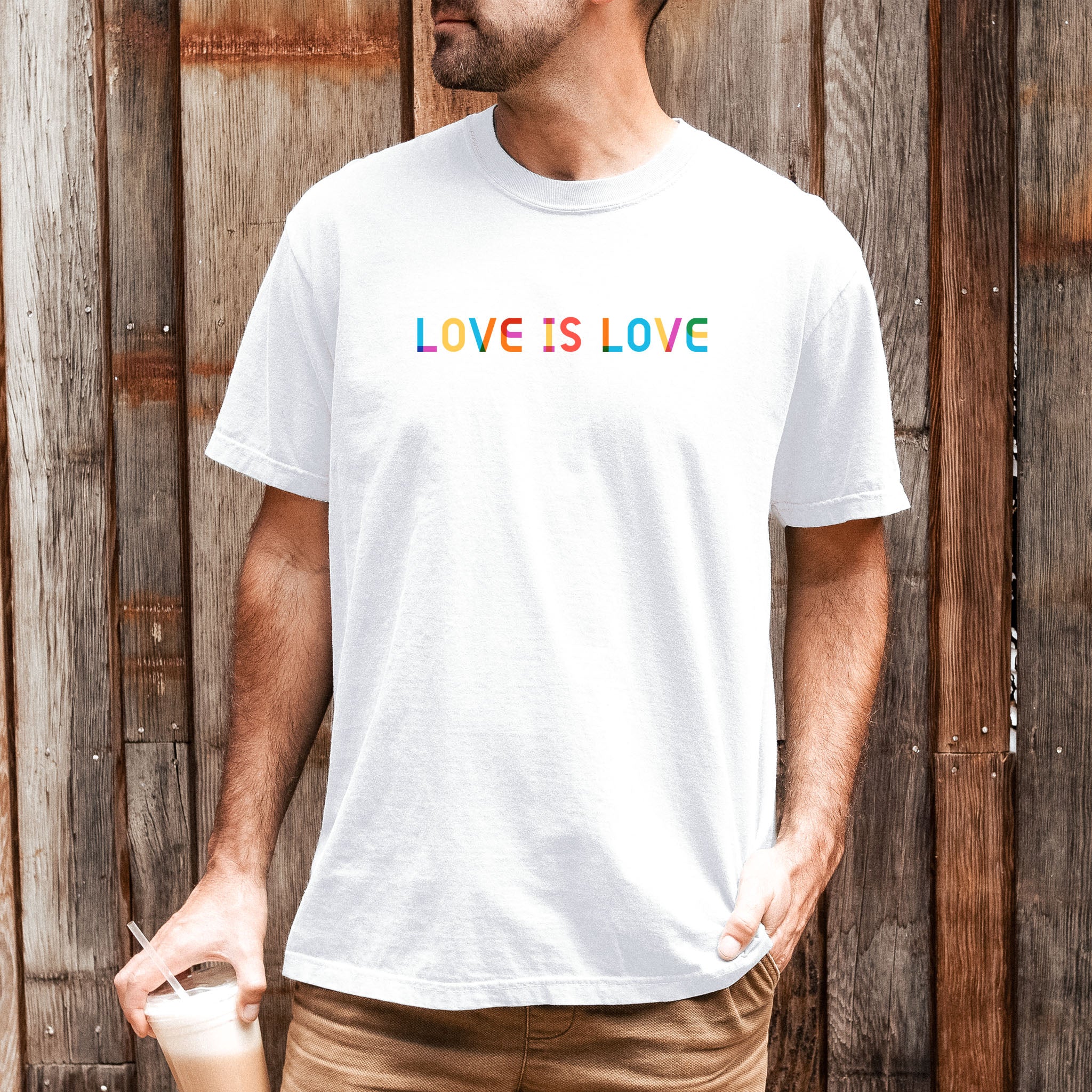 Male model wearing white t-shirt with rainbow “love is love” text designed in the Gilbert font.