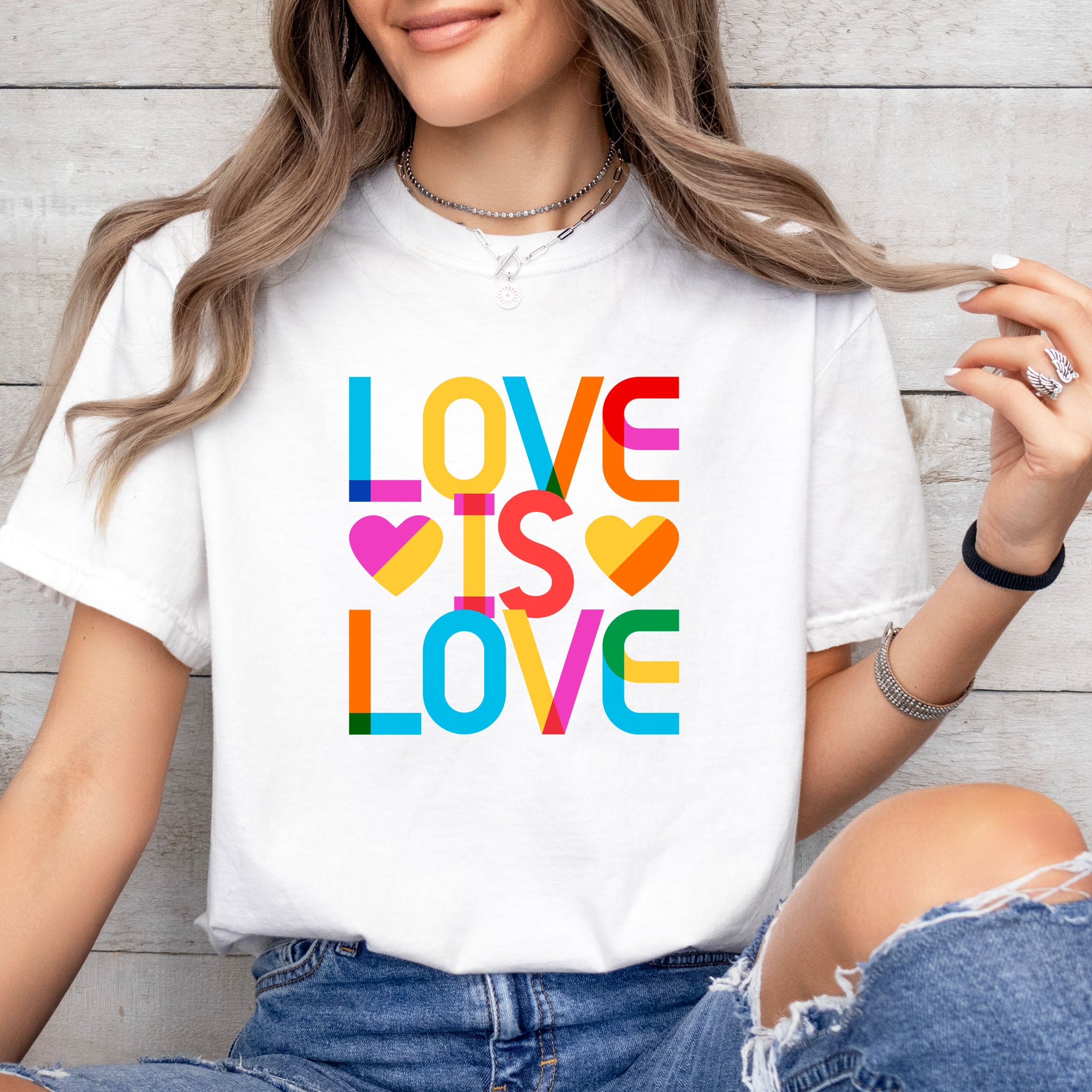 Female model wearing white t-shirt with rainbow “love is love” text designed in the Gilbert font.