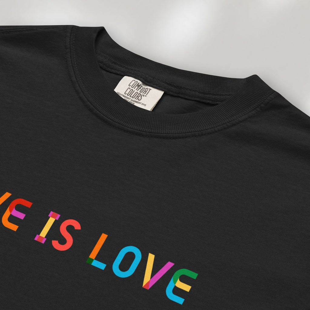 Closeup detail of black oversized t-shirt with rainbow “love is love” text in a single line.