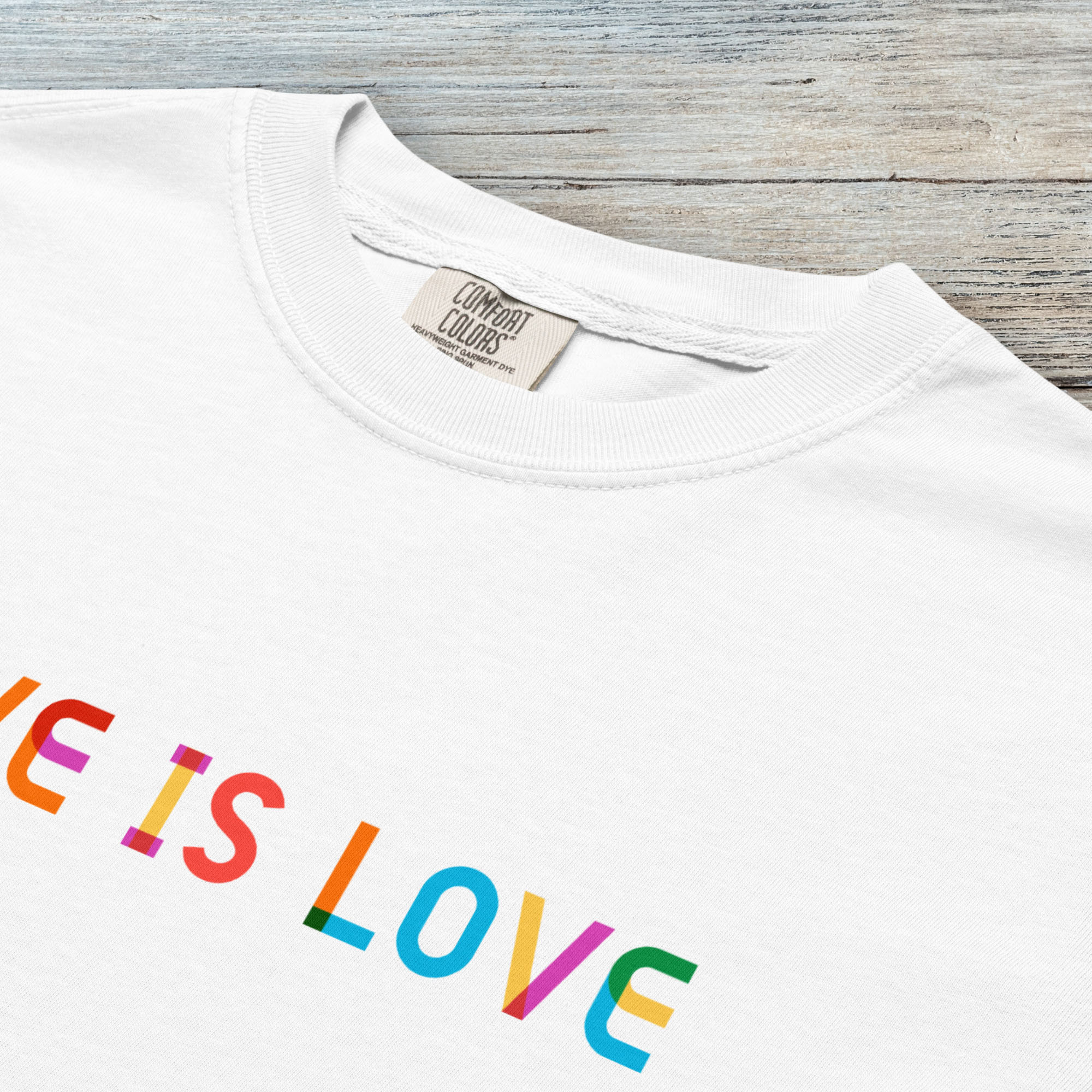 Closeup detail of white t-shirt with rainbow “love is love” text in a single line.