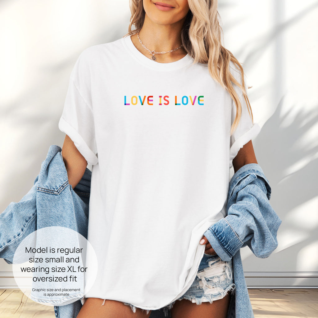 Female model wearing white oversized t-shirt with rainbow “love is love” text in a single line.