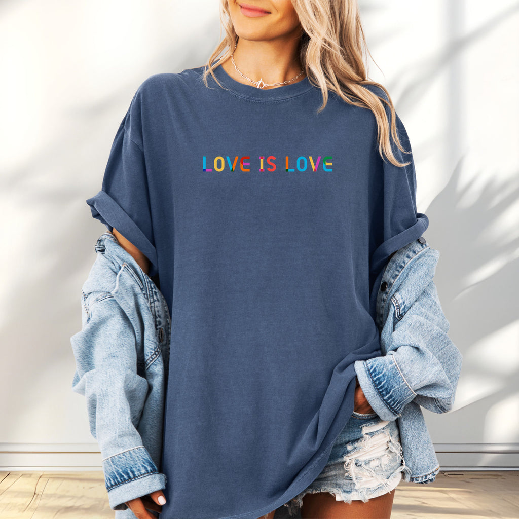 Female model wearing oversized denim t-shirt with rainbow “love is love” text in a single line.