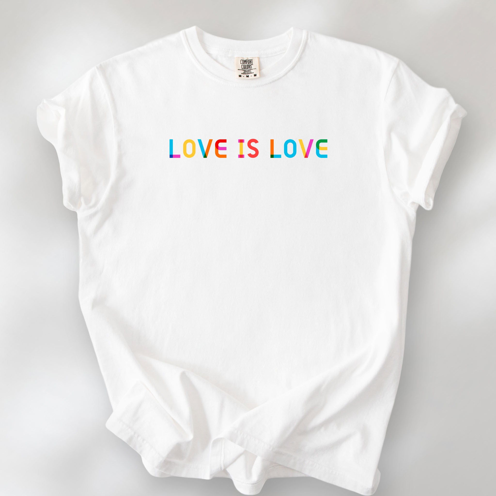White oversized t-shirt with rainbow “love is love” text in a single line.