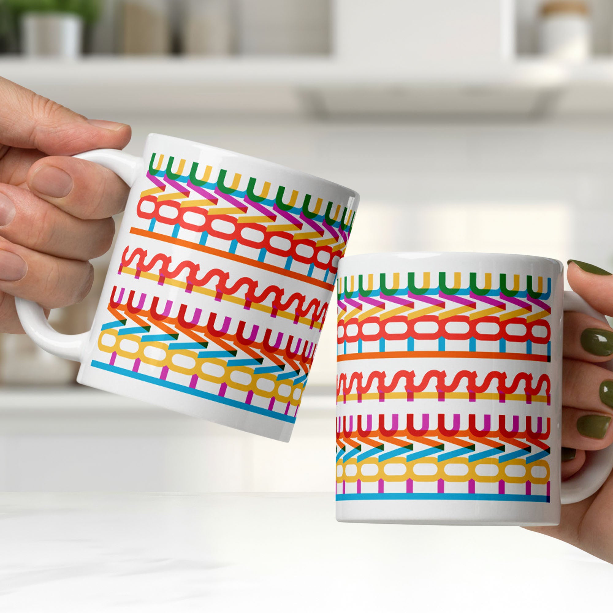 Two people clinking colorful coffee mugs with a repeating hidden “love is love” message in the Gilbert font, featuring bright rainbow-inspired patterns wrapped around the mug.