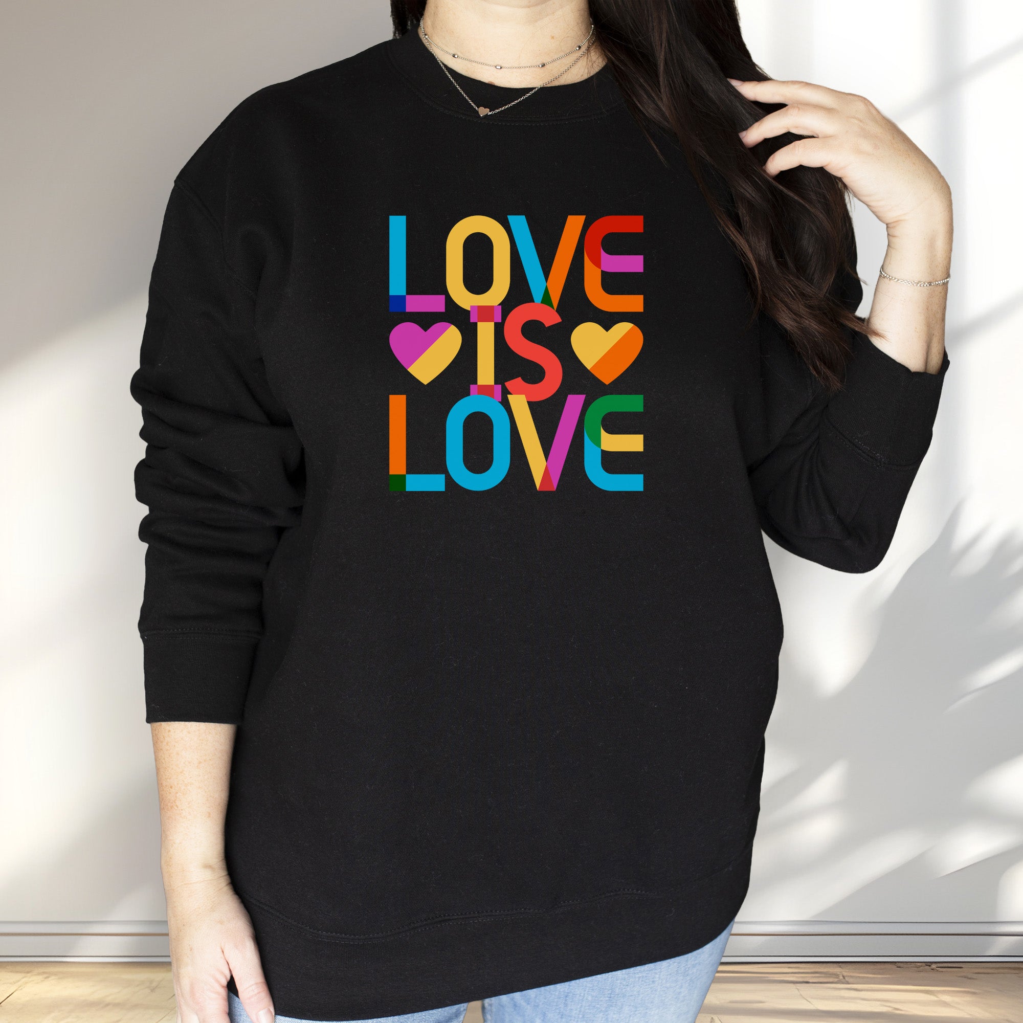 Female model wearing black sweatshirt with rainbow “love is love” text designed in the Gilbert font.
