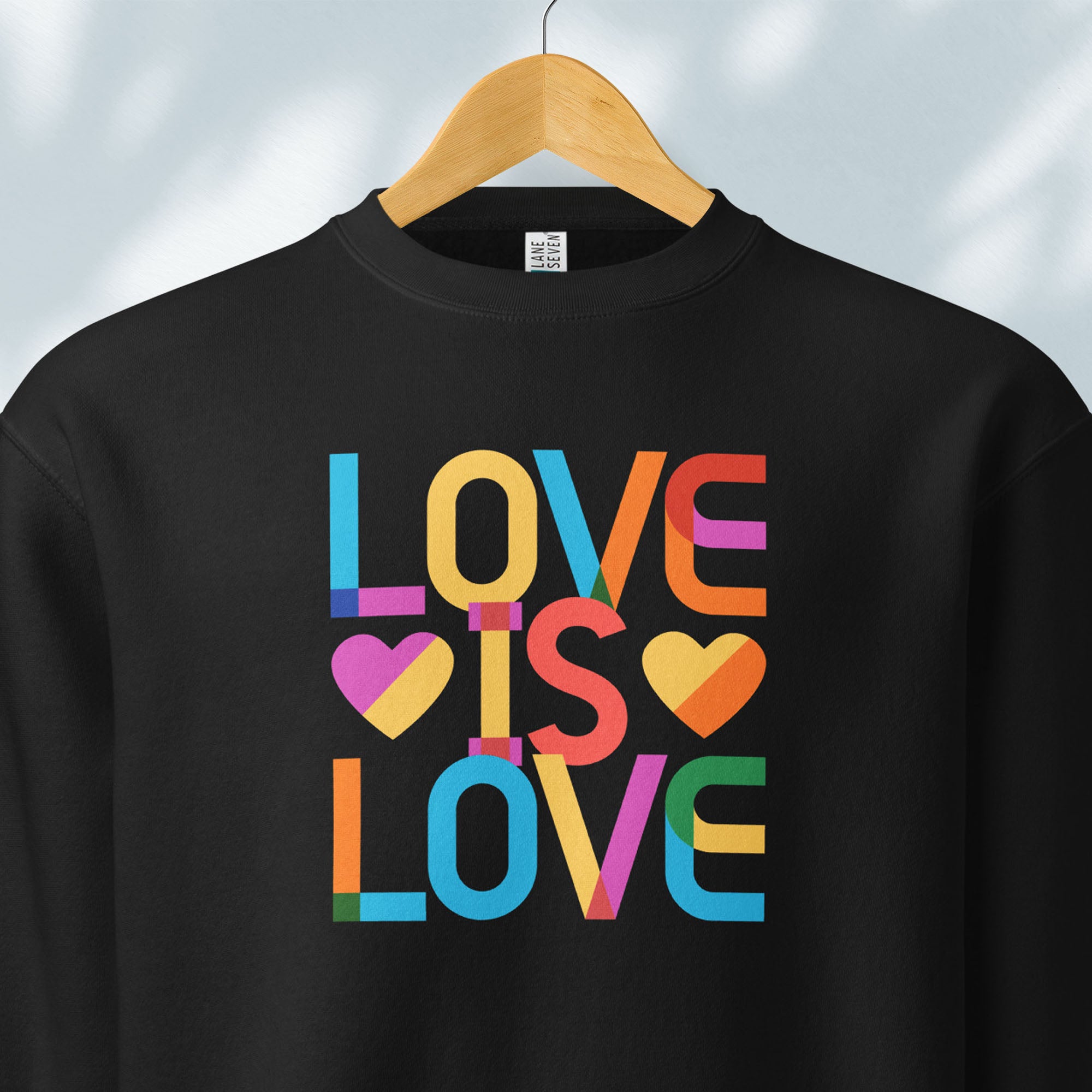 Hanging black sweatshirt with rainbow “love is love” text designed in the Gilbert font.