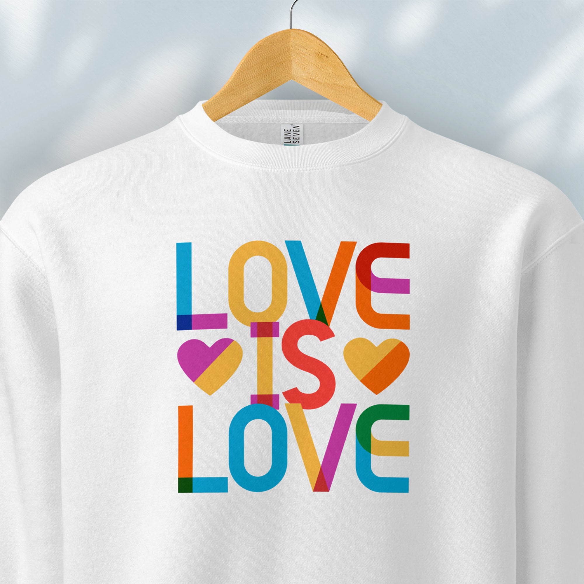 Hanging white sweatshirt with rainbow “love is love” text designed in the Gilbert font.