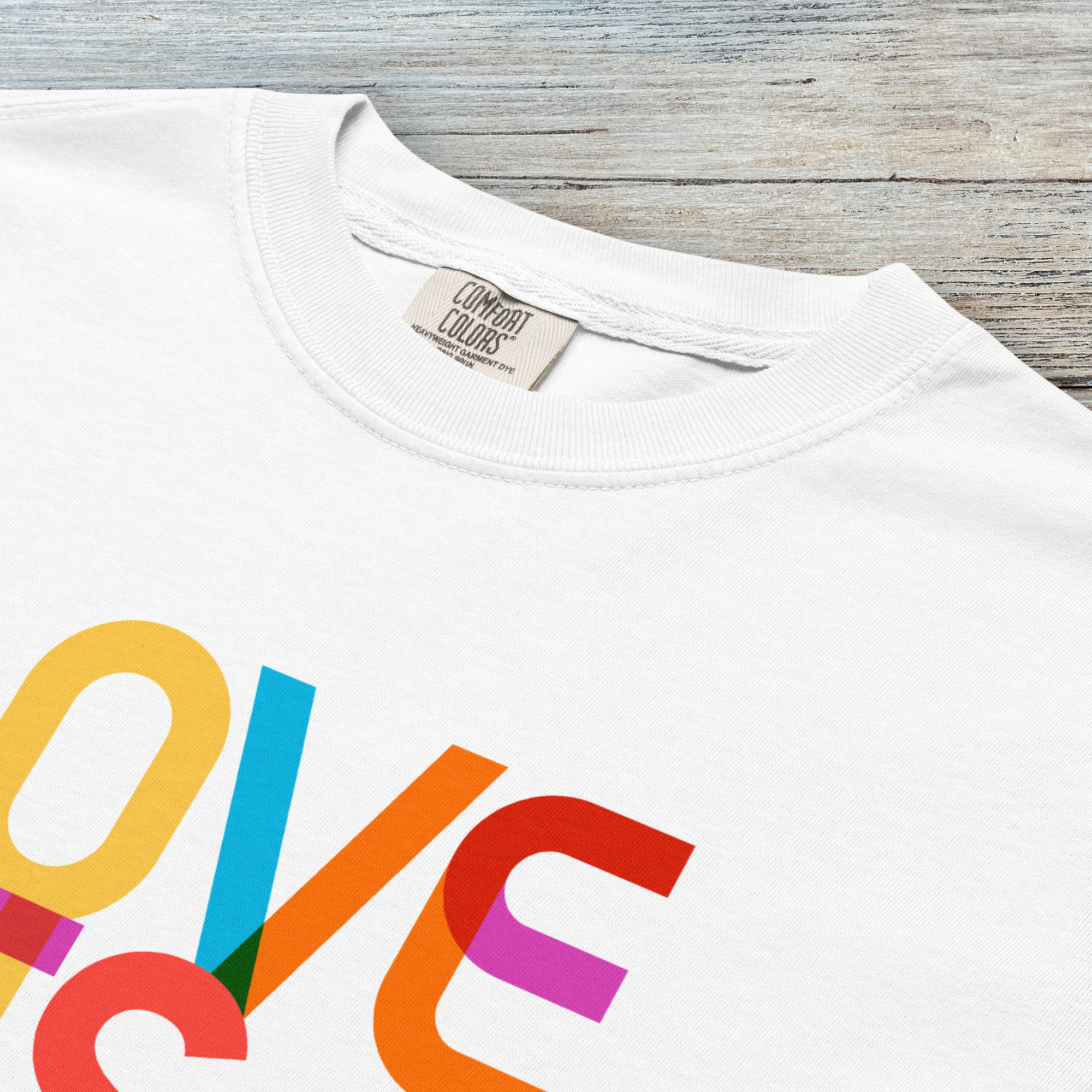 Closeup detail of white t-shirt with rainbow “love is love” stacked styled text.