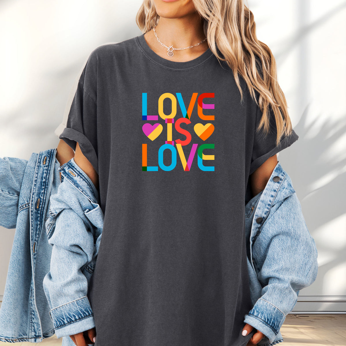 Female model wearing oversized pepper t-shirt with rainbow “love is love” stacked styled text.