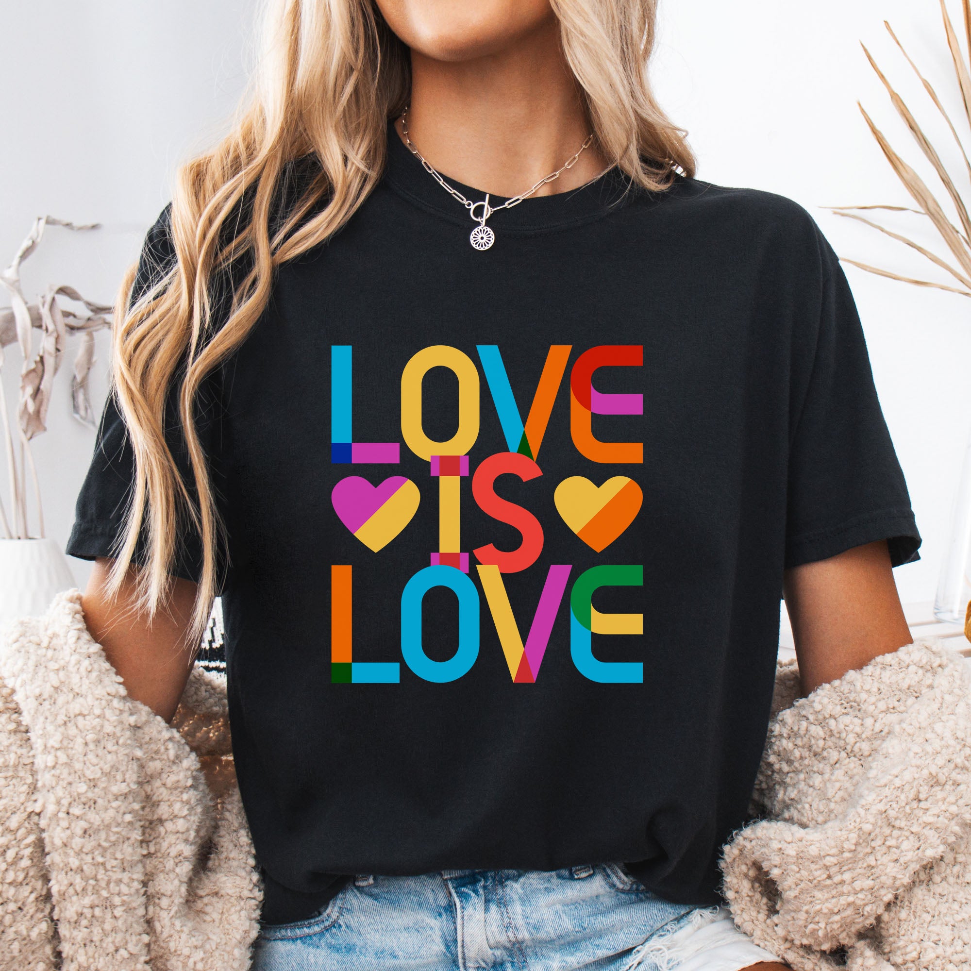 Female model wearing black t-shirt with rainbow “love is love” stacked styled text.