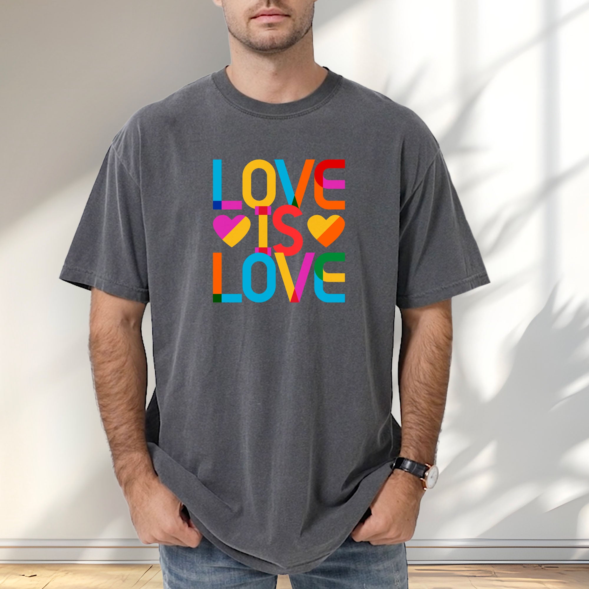 Male model wearing pepper t-shirt with rainbow “love is love” text block.