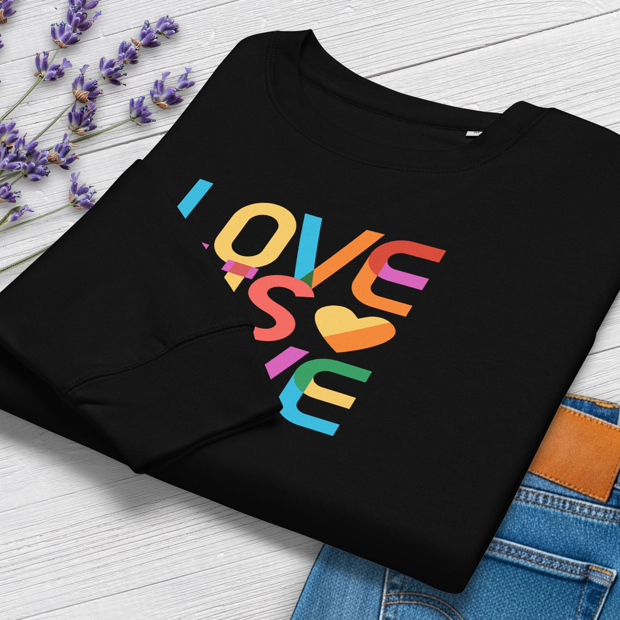 Folded black women's sweatshirt with rainbow “love is love” text designed in the Gilbert font, showing cuff detail.