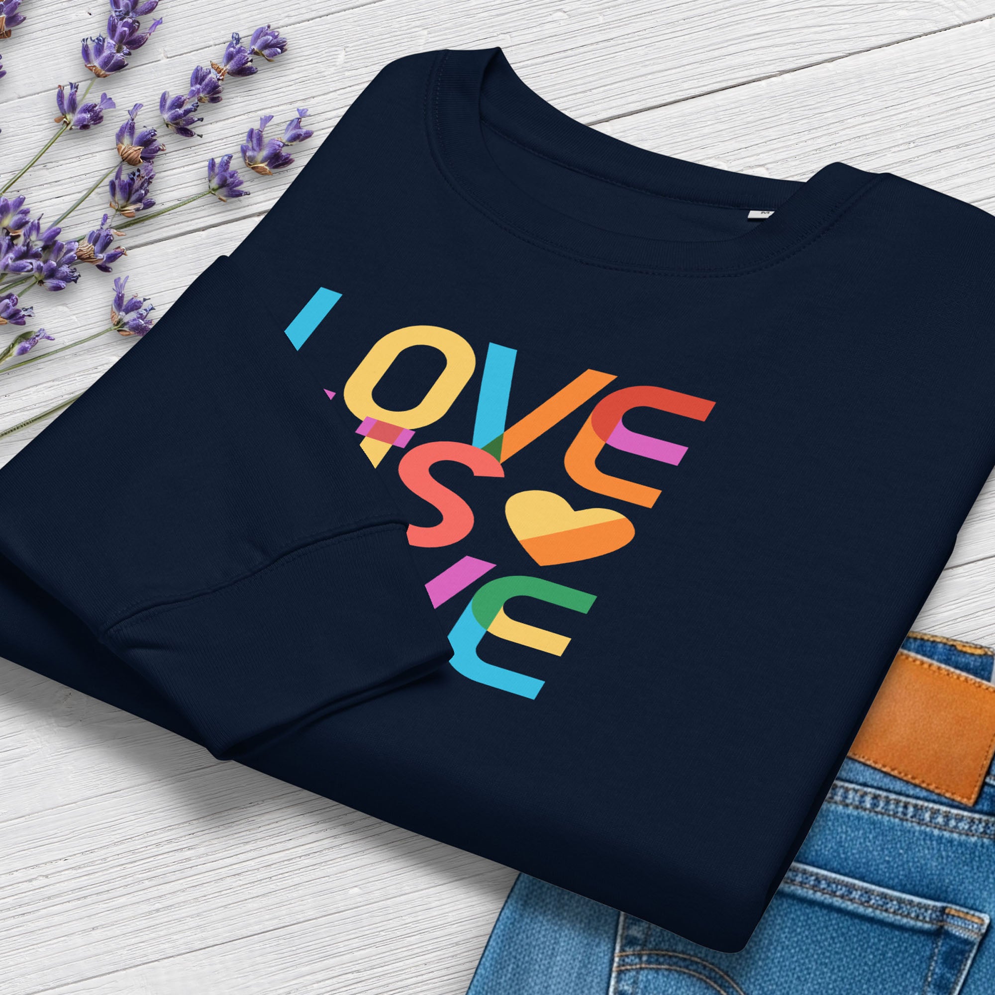 Folded navy women's sweatshirt with rainbow “love is love” text designed in the Gilbert font, showing cuff detail.