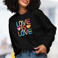 Front view of female model wearing black women's sweatshirt with rainbow “love is love” text designed in the Gilbert font.