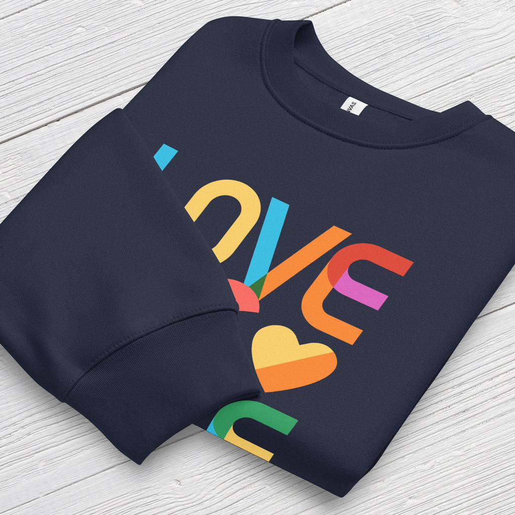 Folded navy t-shirt with rainbow “love is love” text designed in the Gilbert font, showing cuff detail.