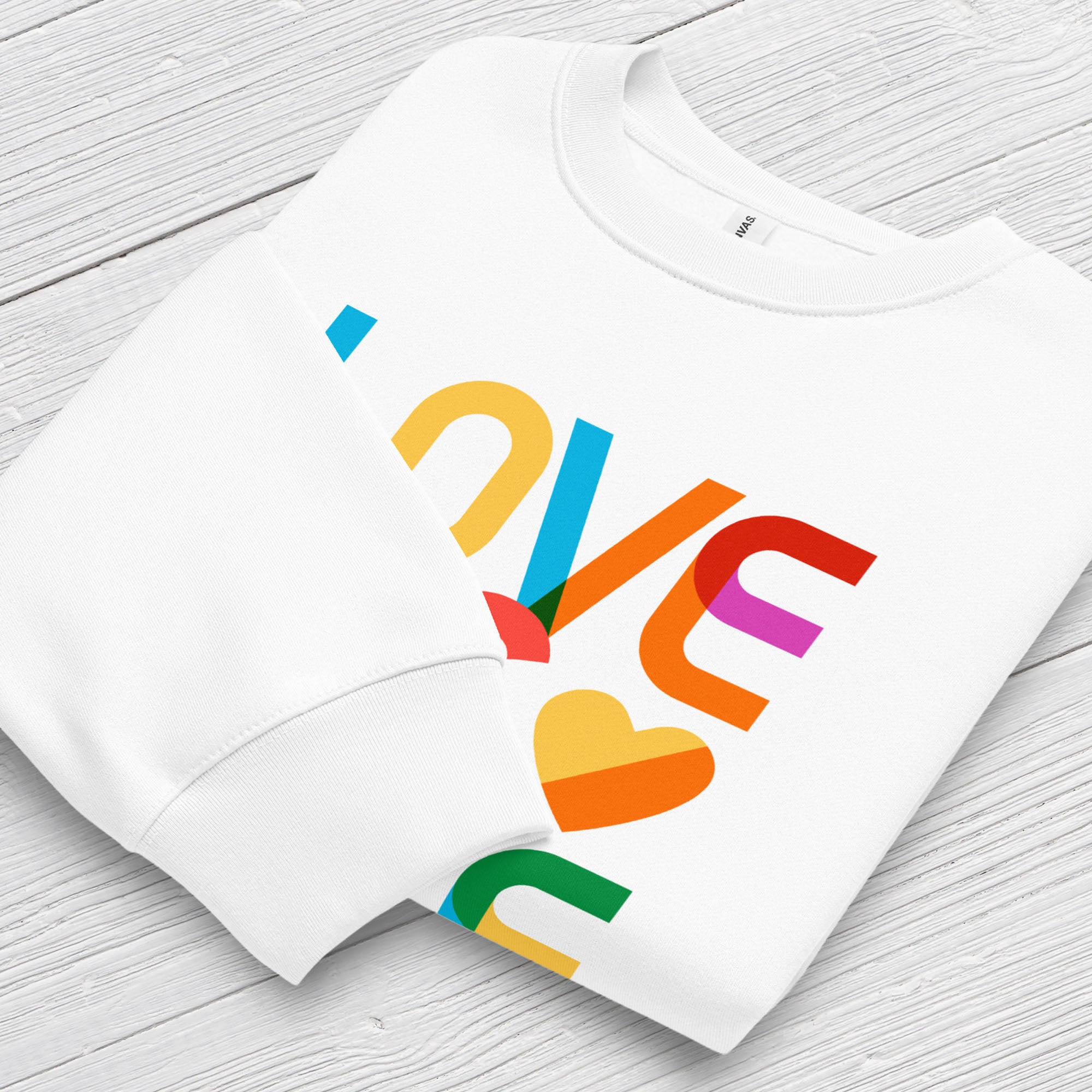 Folded white t-shirt with rainbow “love is love” text designed in the Gilbert font, showing cuff detail.