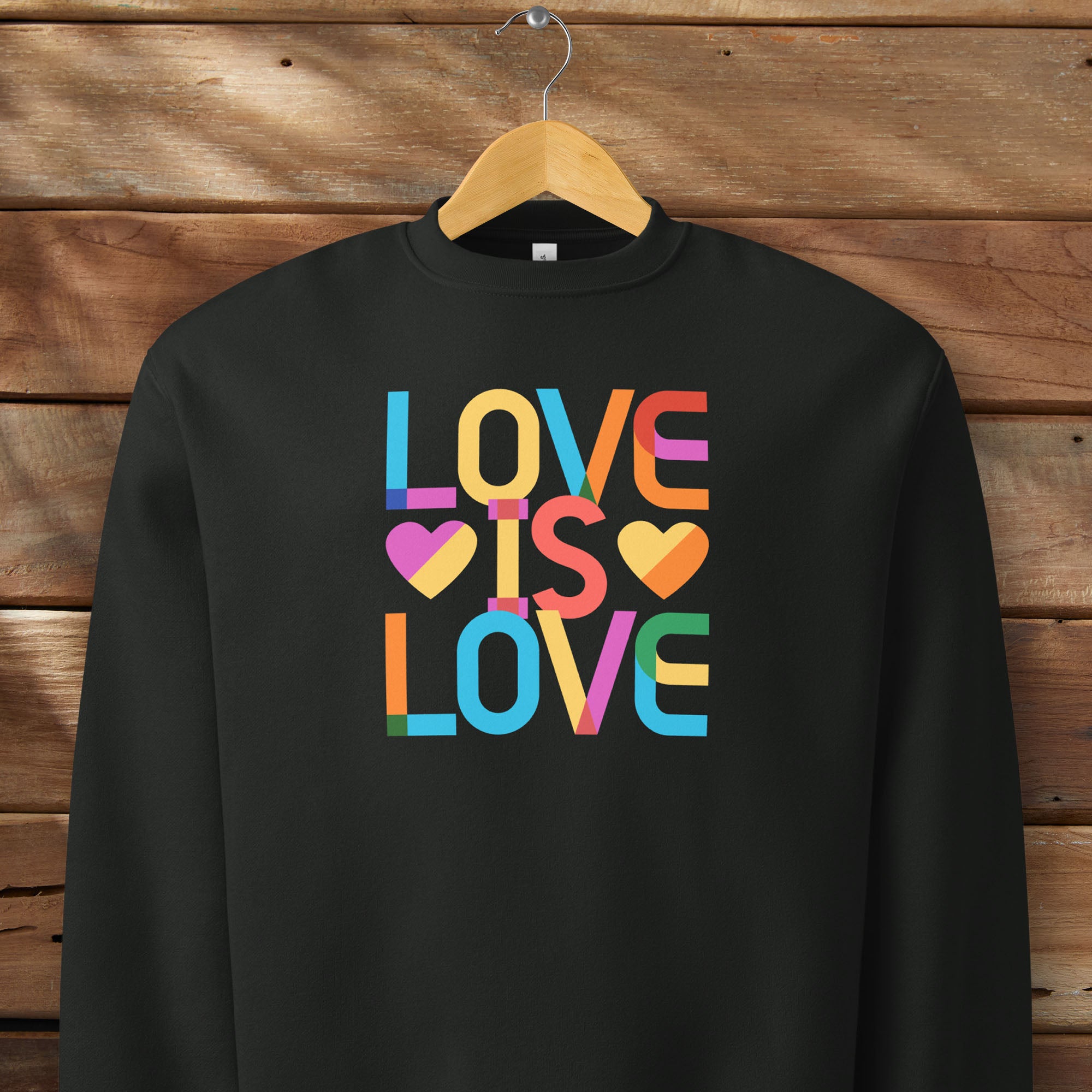 Hanging black t-shirt with rainbow “love is love” text designed in the Gilbert font.