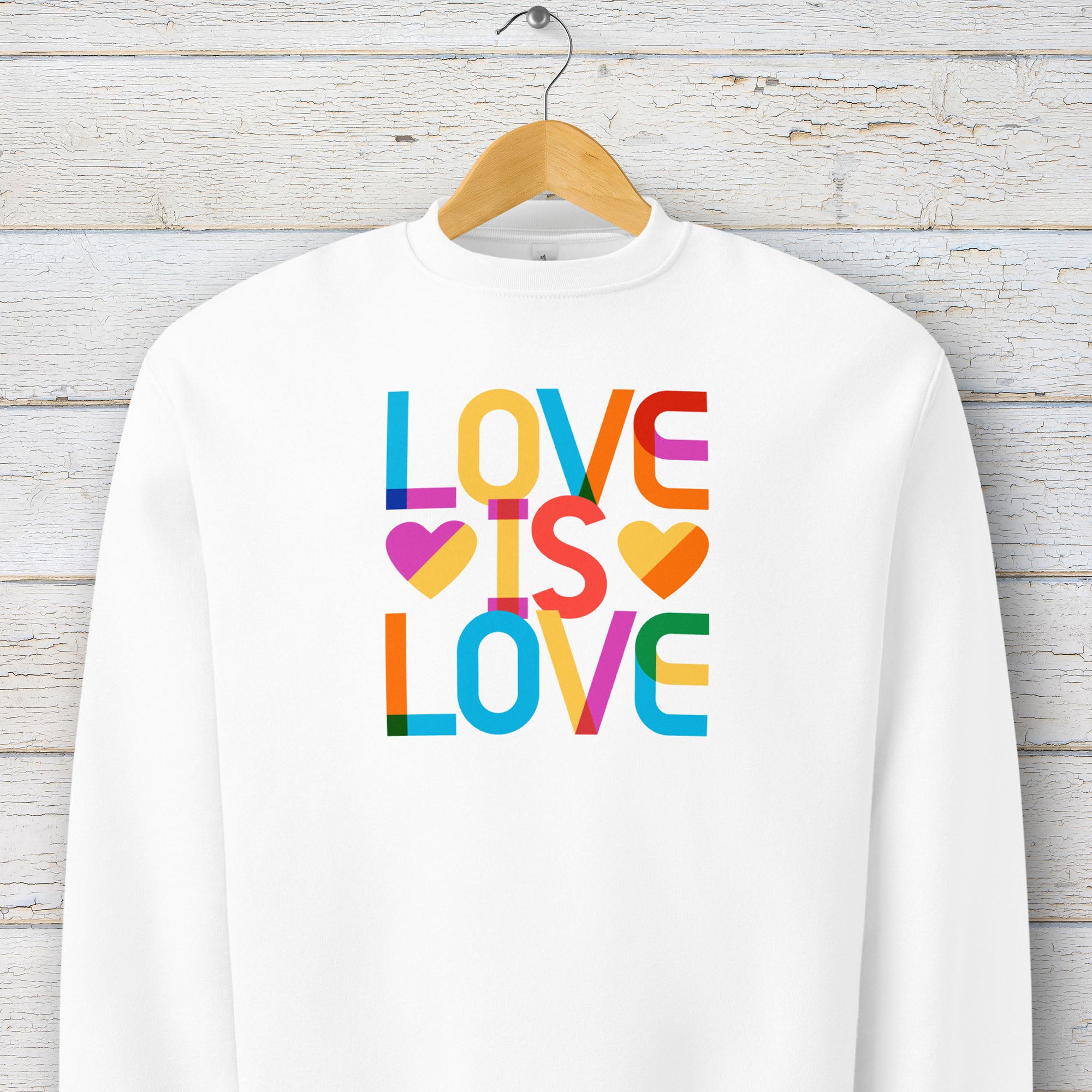Hanging white t-shirt with rainbow “love is love” text designed in the Gilbert font.