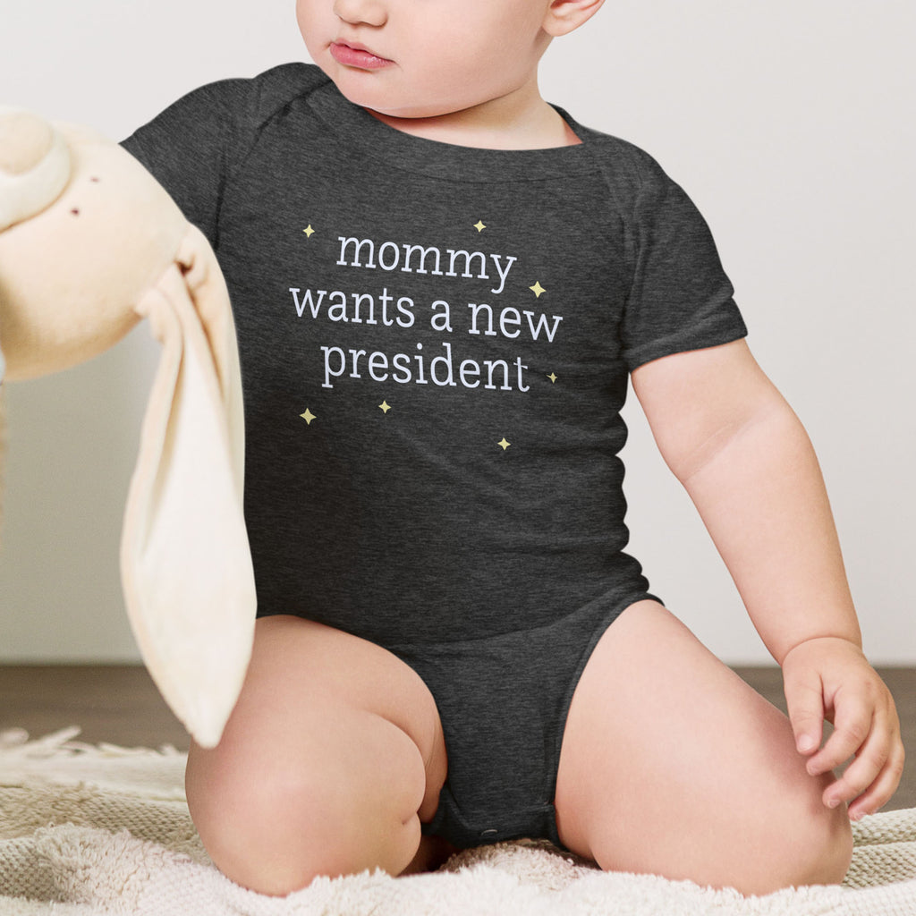 Baby wearing dark heather grey baby short sleeve one piece with light text reading “mommy wants a new president."