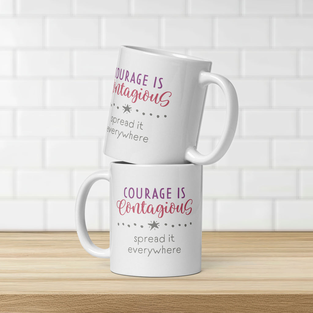 Two stacked mugs on counter with styled text graphic that reads "courage is contagious – spread it everywhere". Graphic is same on both sides of mug.
